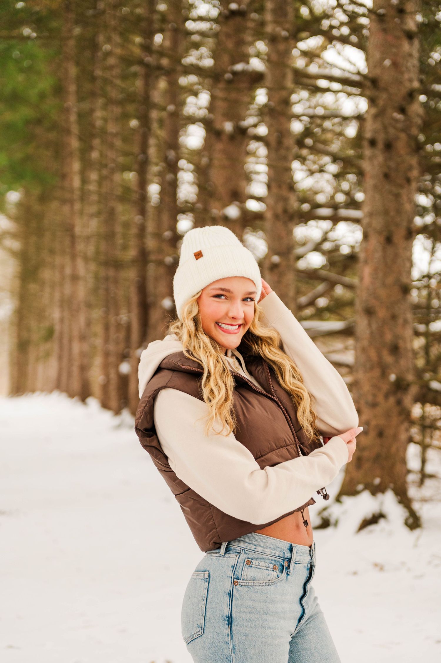 Candid winter fashion photography in a snow-covered pine forest setting.