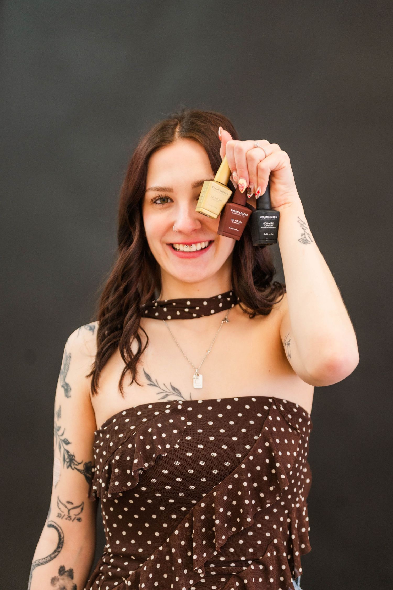 A person in a polka dot dress poses with props against a dark background.