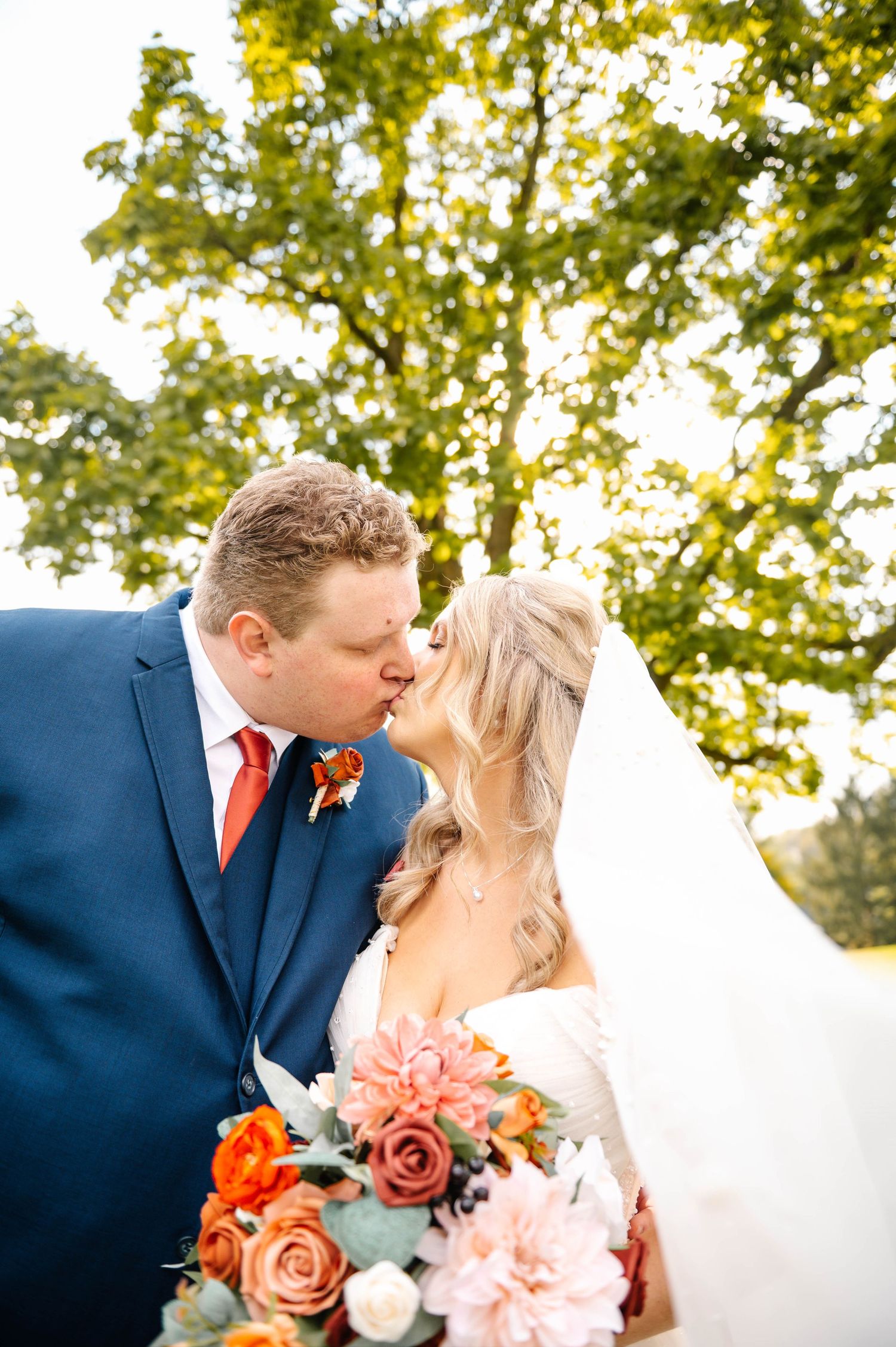 Romantic autumn wedding portraits with coral and pink bouquet details.