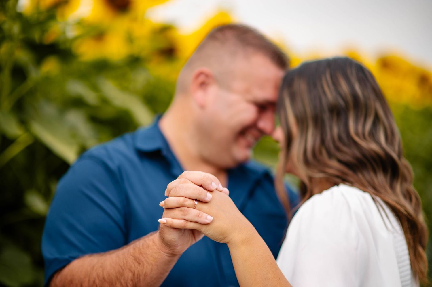 A couple sharing an intimate dance among rows of bright sunflowers.