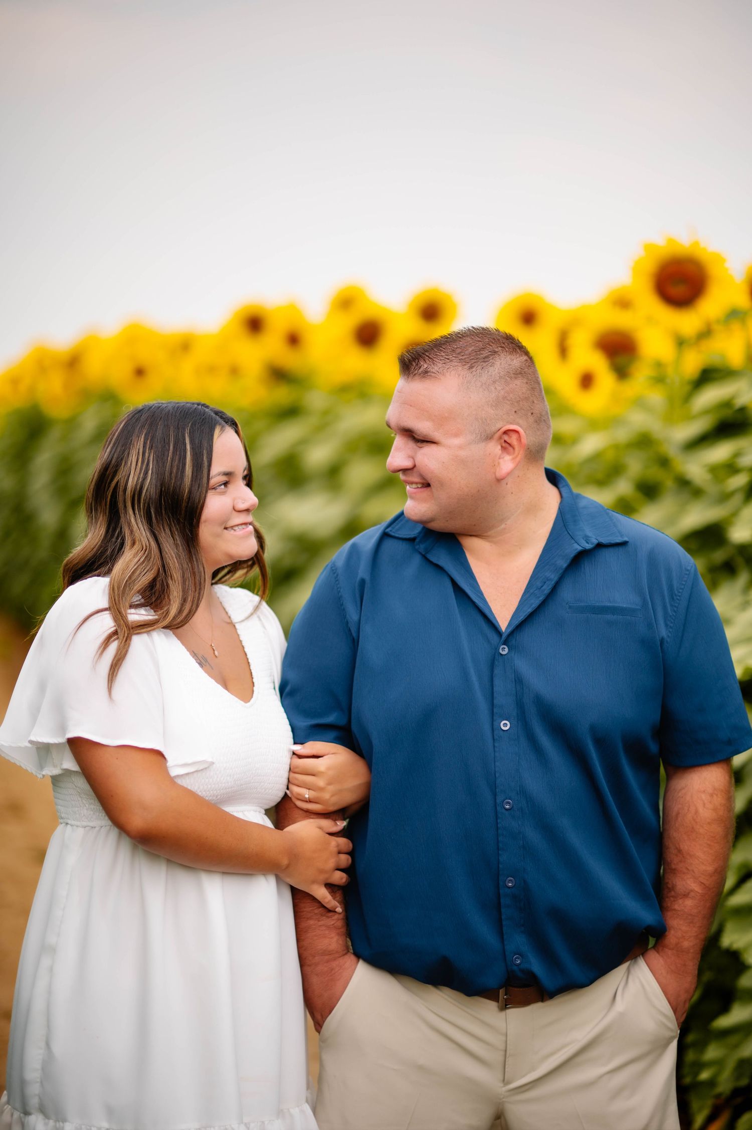 A couple sharing a tender moment while standing in a vibrant sunflower field.