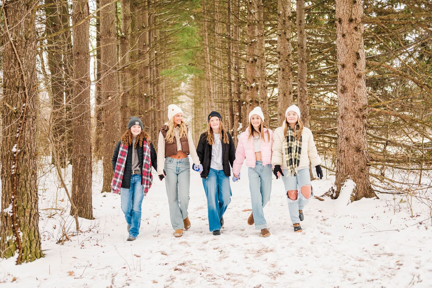 Group photo session in a snowy forest with multiple people wearing coordinated winter outfits.