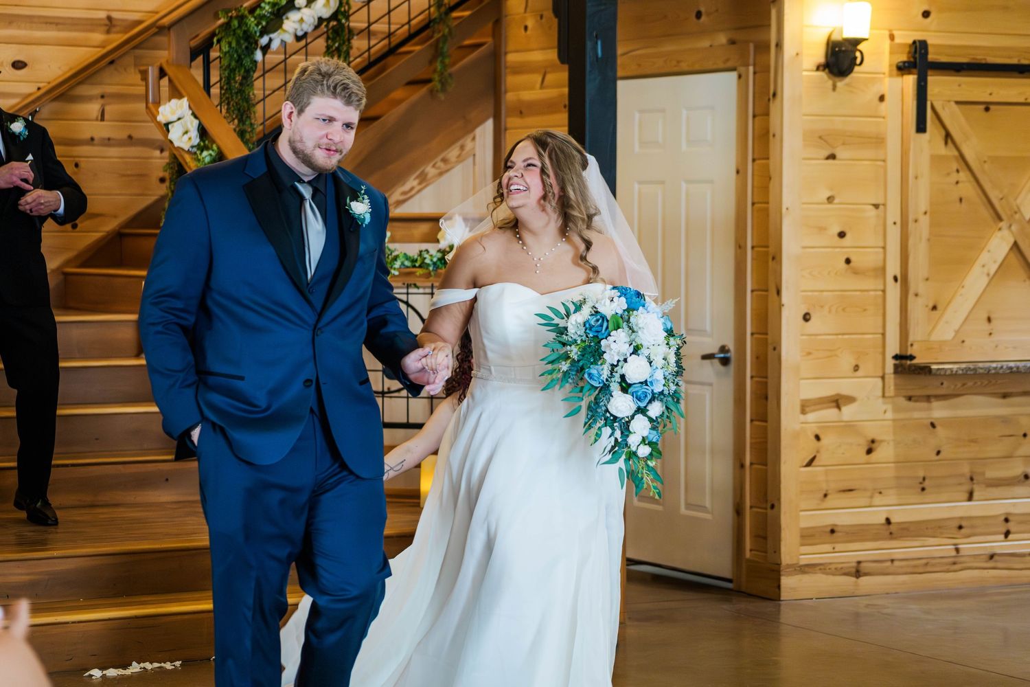 Rustic barn wedding ceremony with wooden walls and decorative lighting.