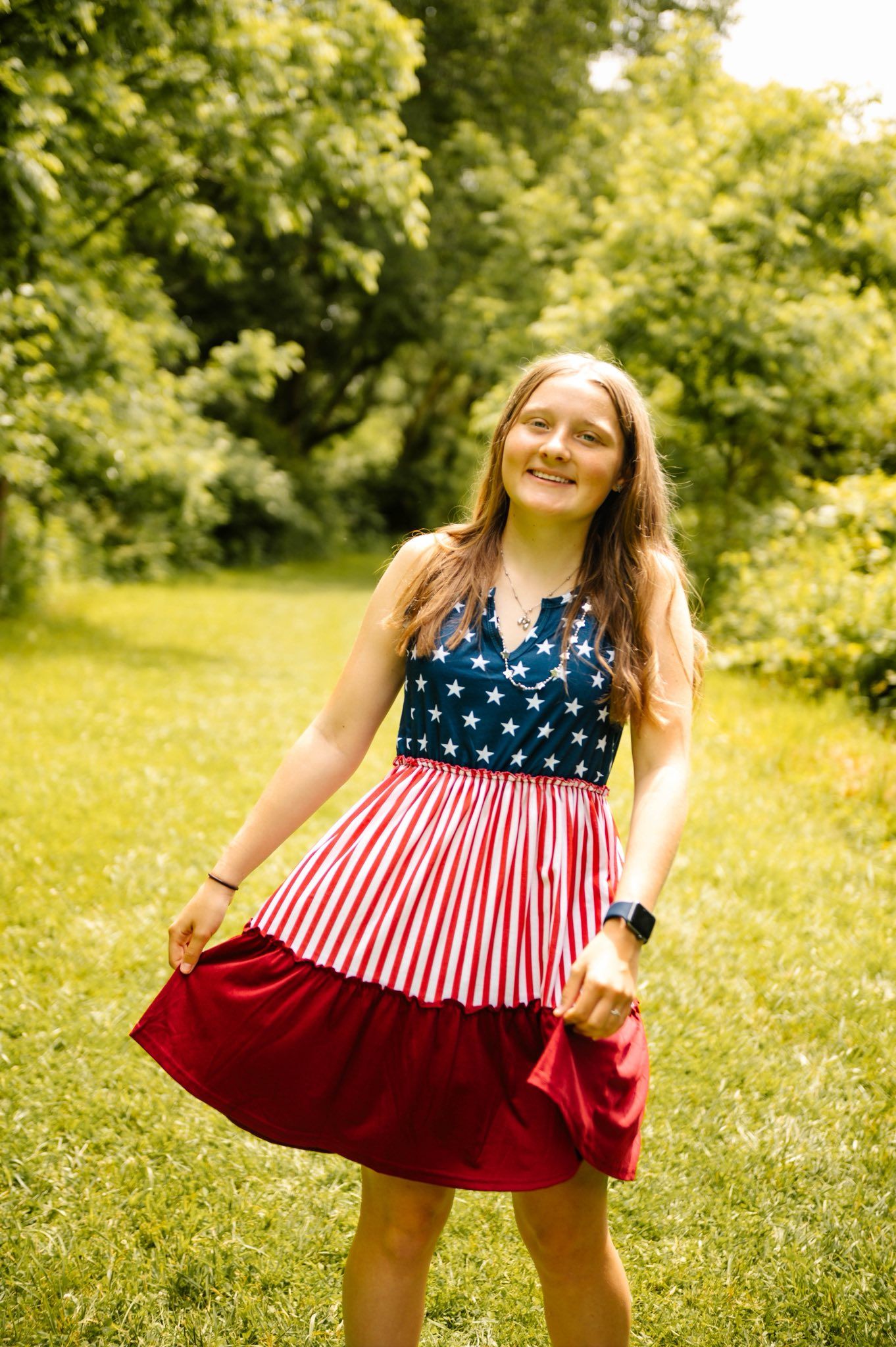 A stars and stripes patterned dress twirls in a sunny summer field.