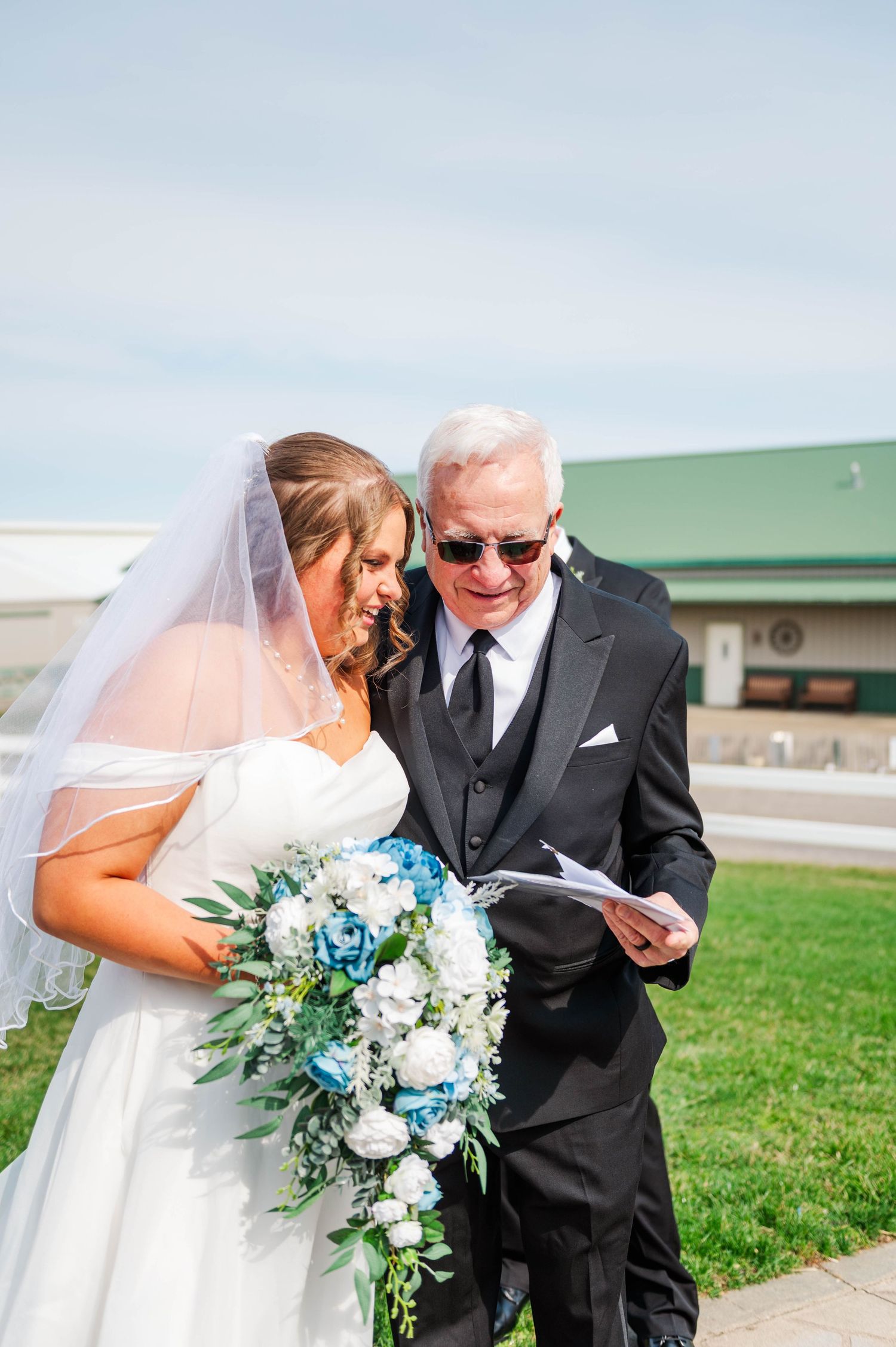 A tender moment between a bride and someone in formal attire during an outdoor ceremony.