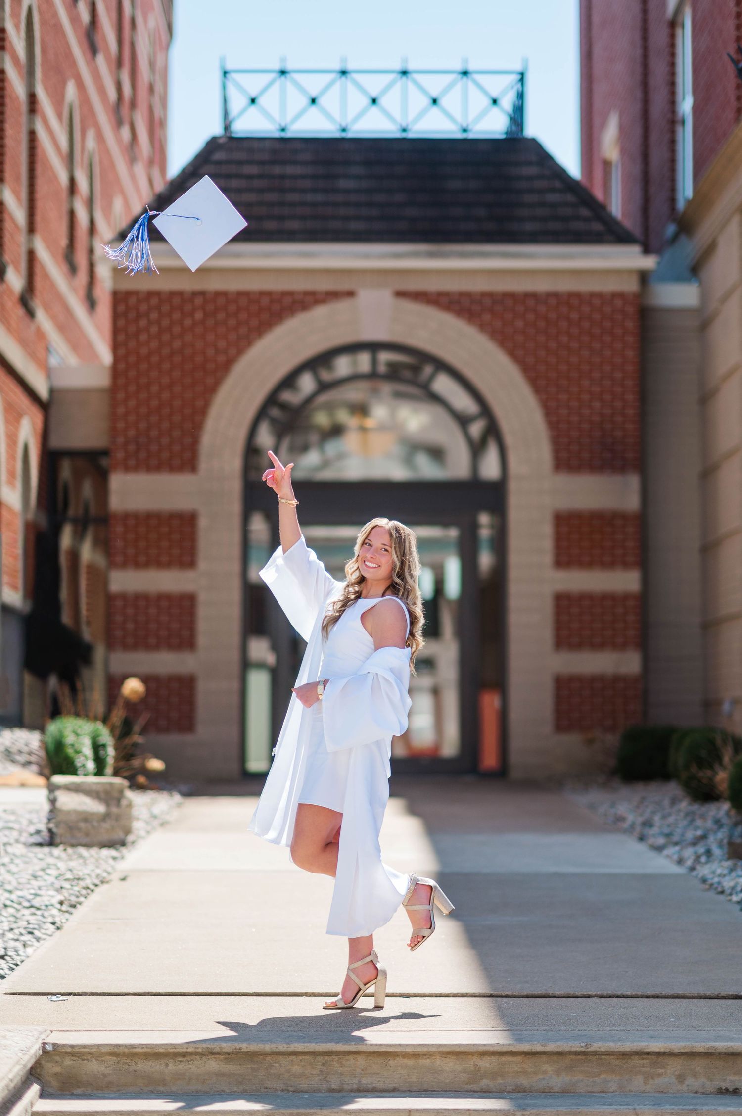 Celebratory graduation cap toss sequence outside brick university building.