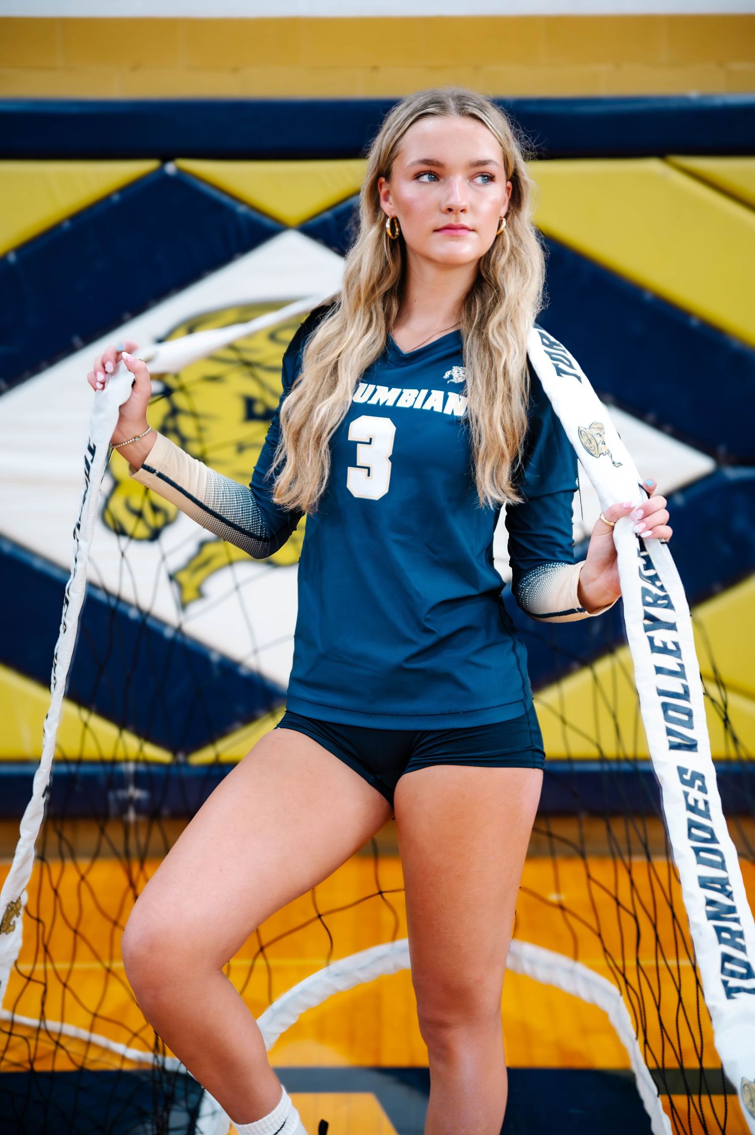 Athletic photoshoot featuring volleyball net and school sports equipment.