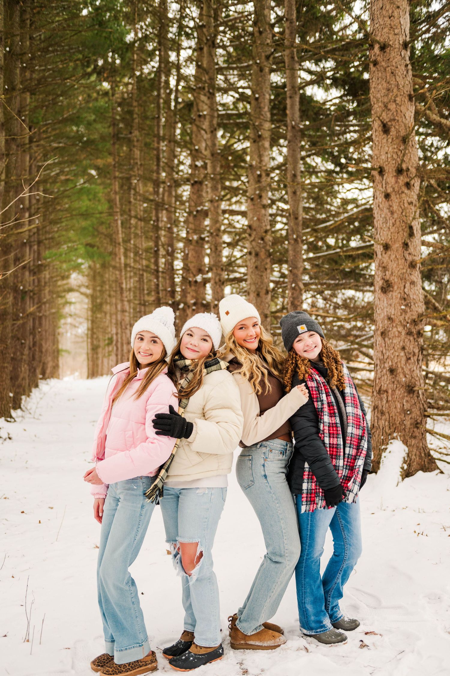 Group photo session in snow-covered pine forest with matching casual winter outfits.