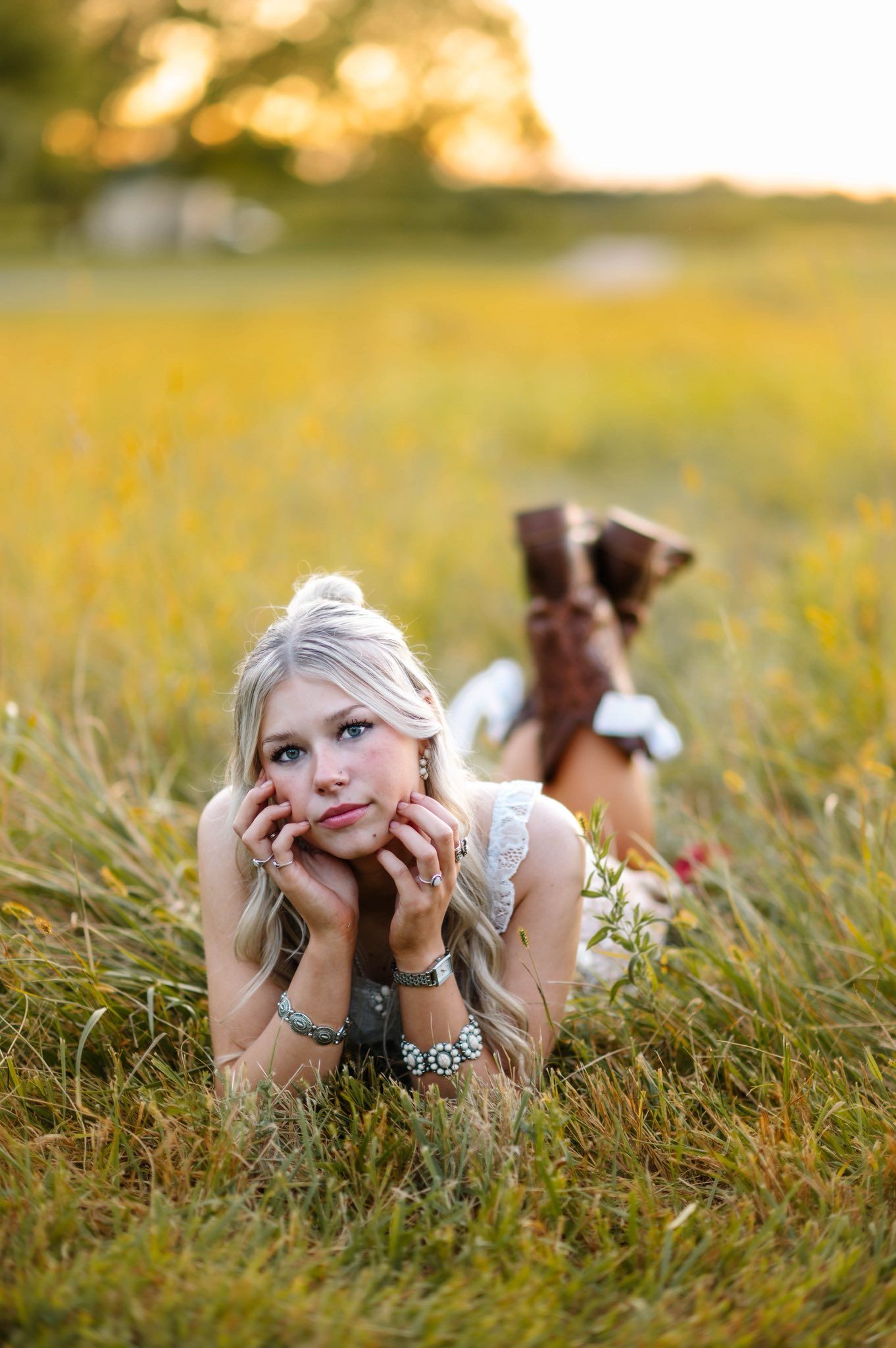A dreamy summer portrait in a golden field with boots and bracelets at sunset.