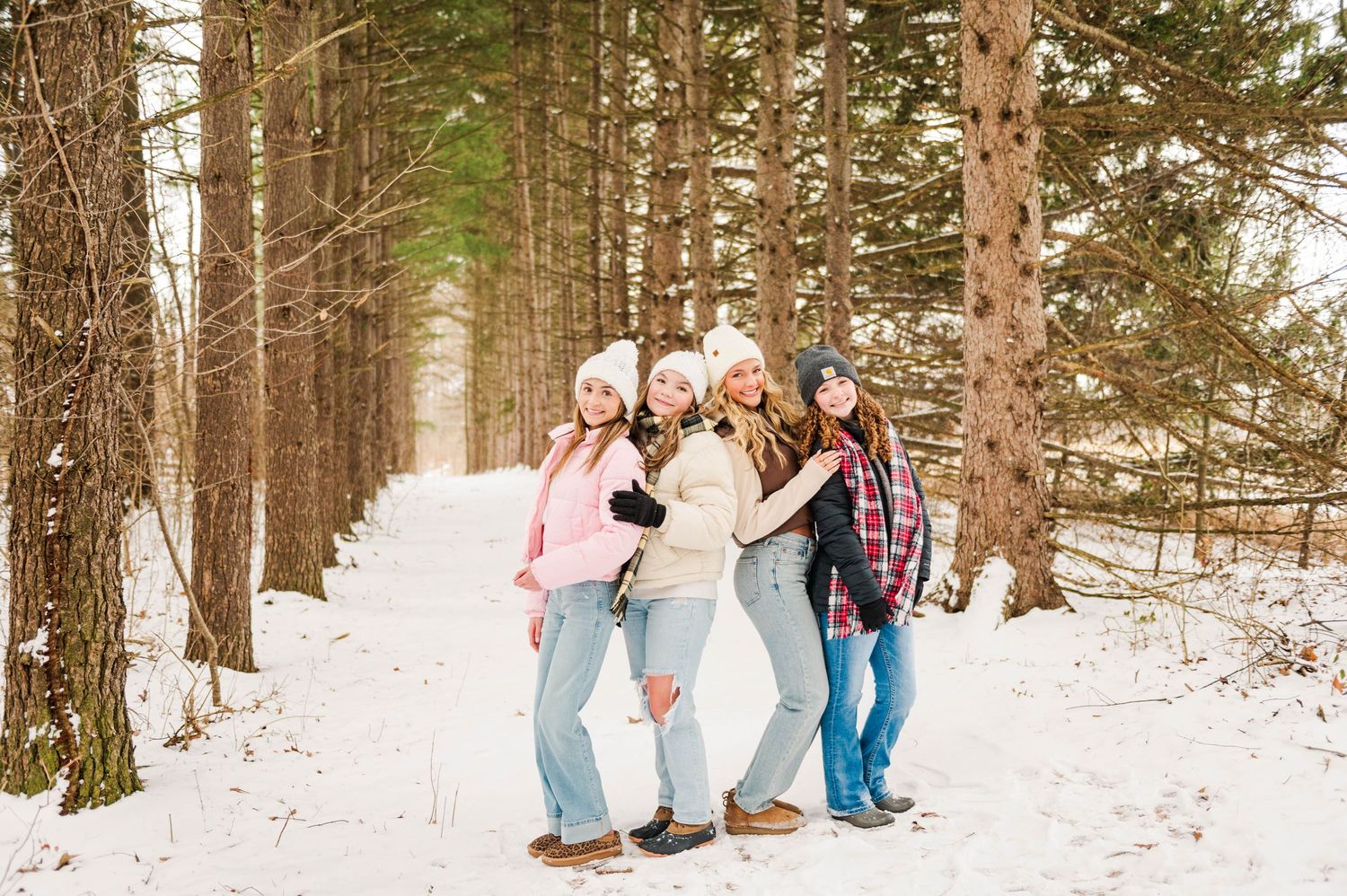 Friends posing together on a snowy forest path during winter.