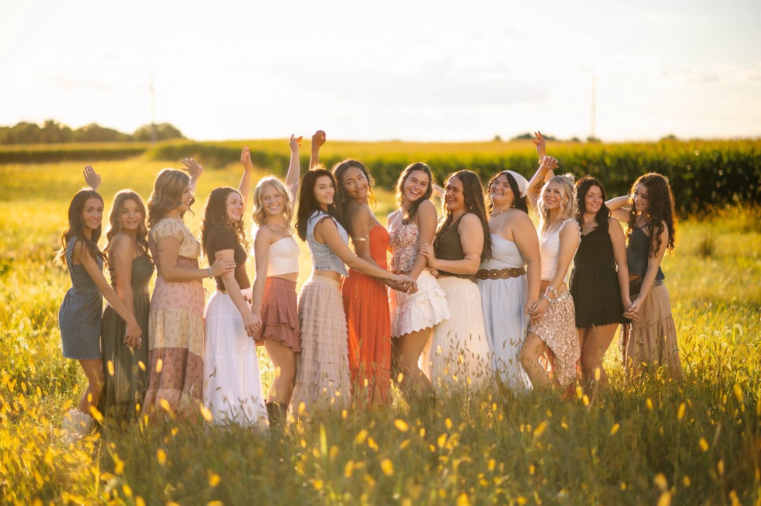 A large group poses together in a sun-drenched meadow filled with wildflowers.