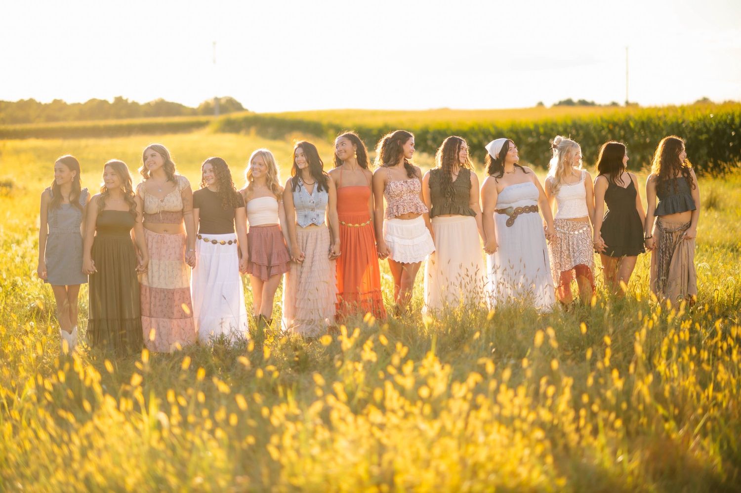 Line of people standing in a field backlit by warm sunset light.
