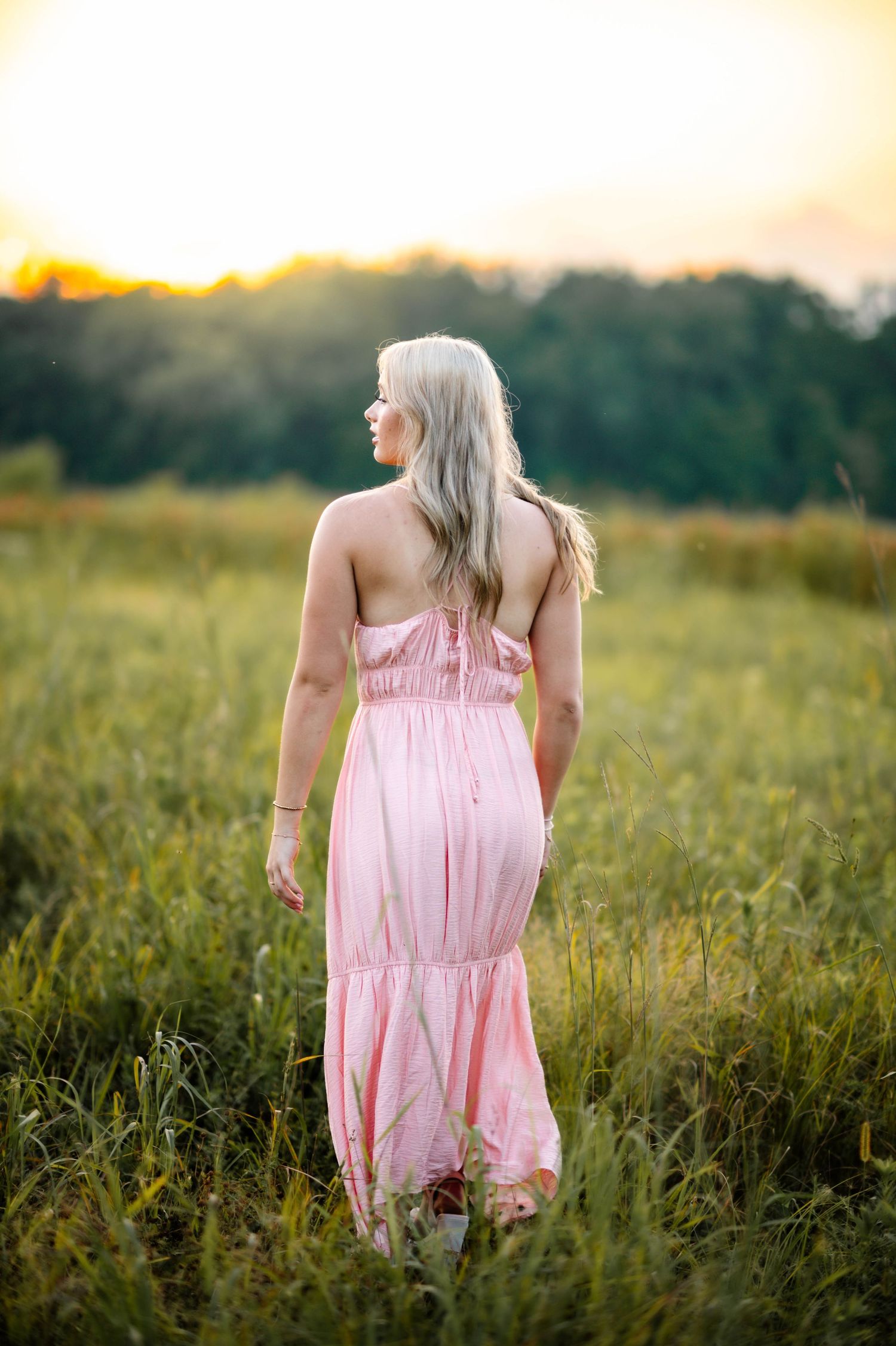 A flowing pink dress catches the evening light in a wildflower meadow.