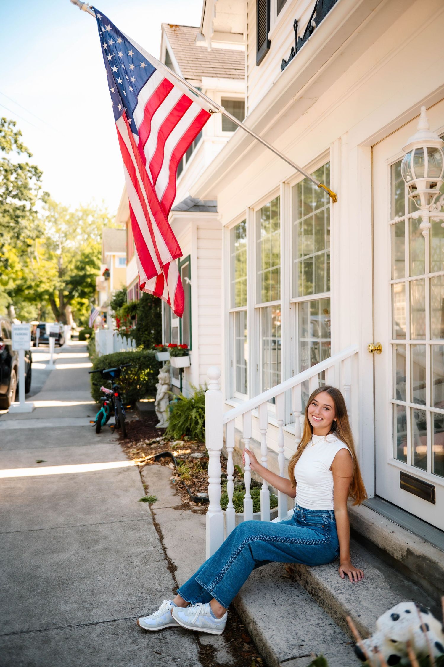 American flags wave outside a white building with classic colonial architecture.