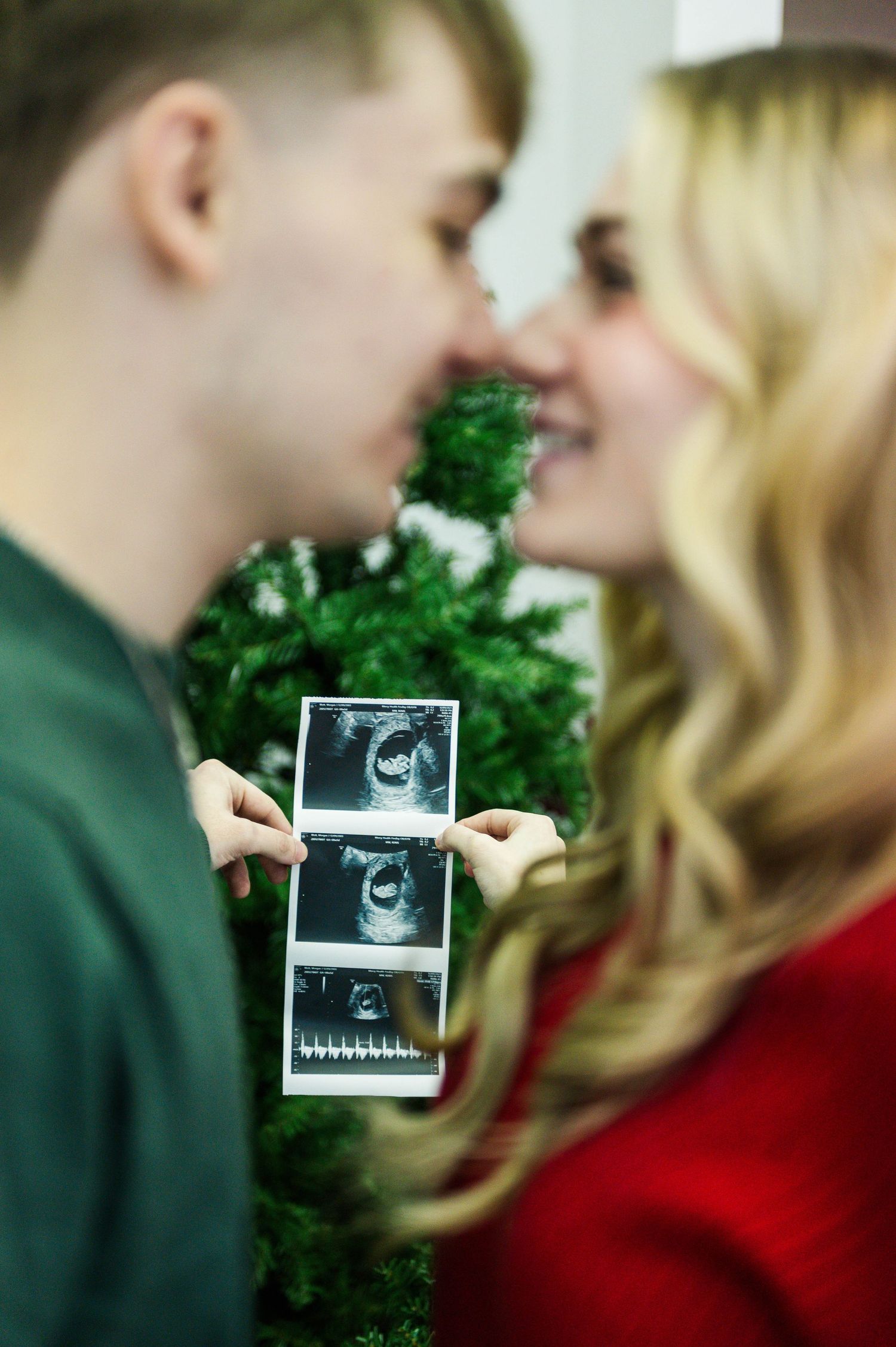 Close up of couple sharing intimate moment while holding ultrasound photo.
