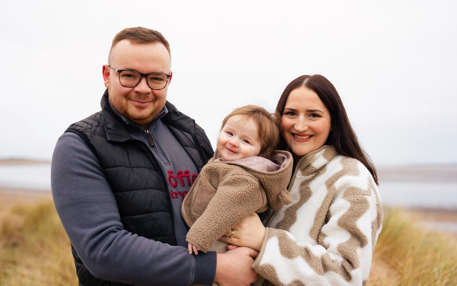 Dad, baby, and mom smiling during a warm, natural lifestyle photoshoot