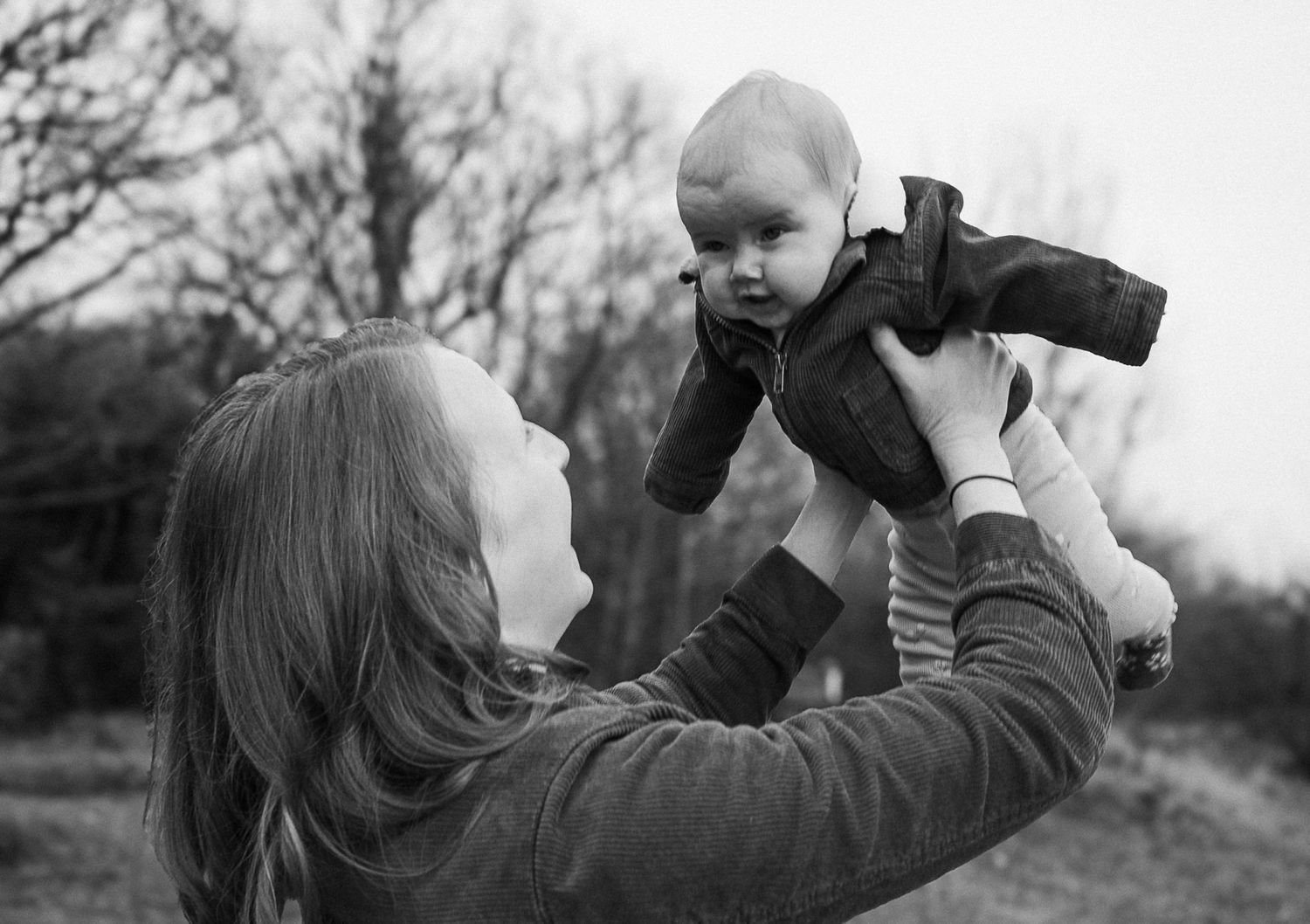 mum lifting baby in the air during their photo session in the woodlands