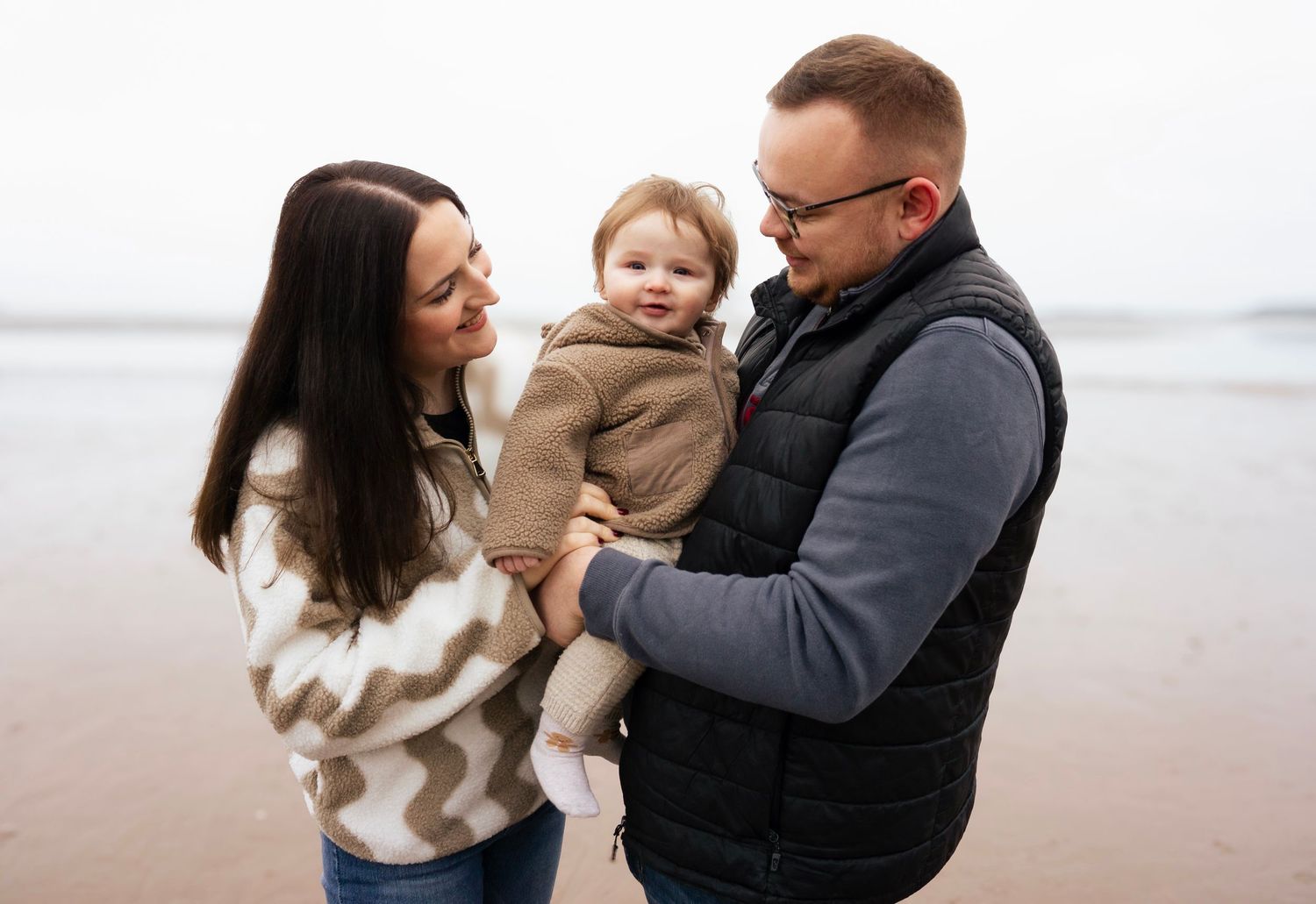 Dad and mom smiling at baby during a warm, natural lifestyle photoshoot