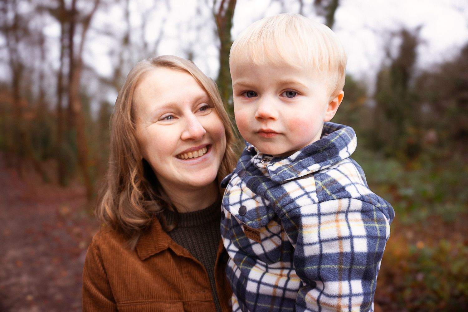 happy mum and son smiling during their photo session in the woodlands