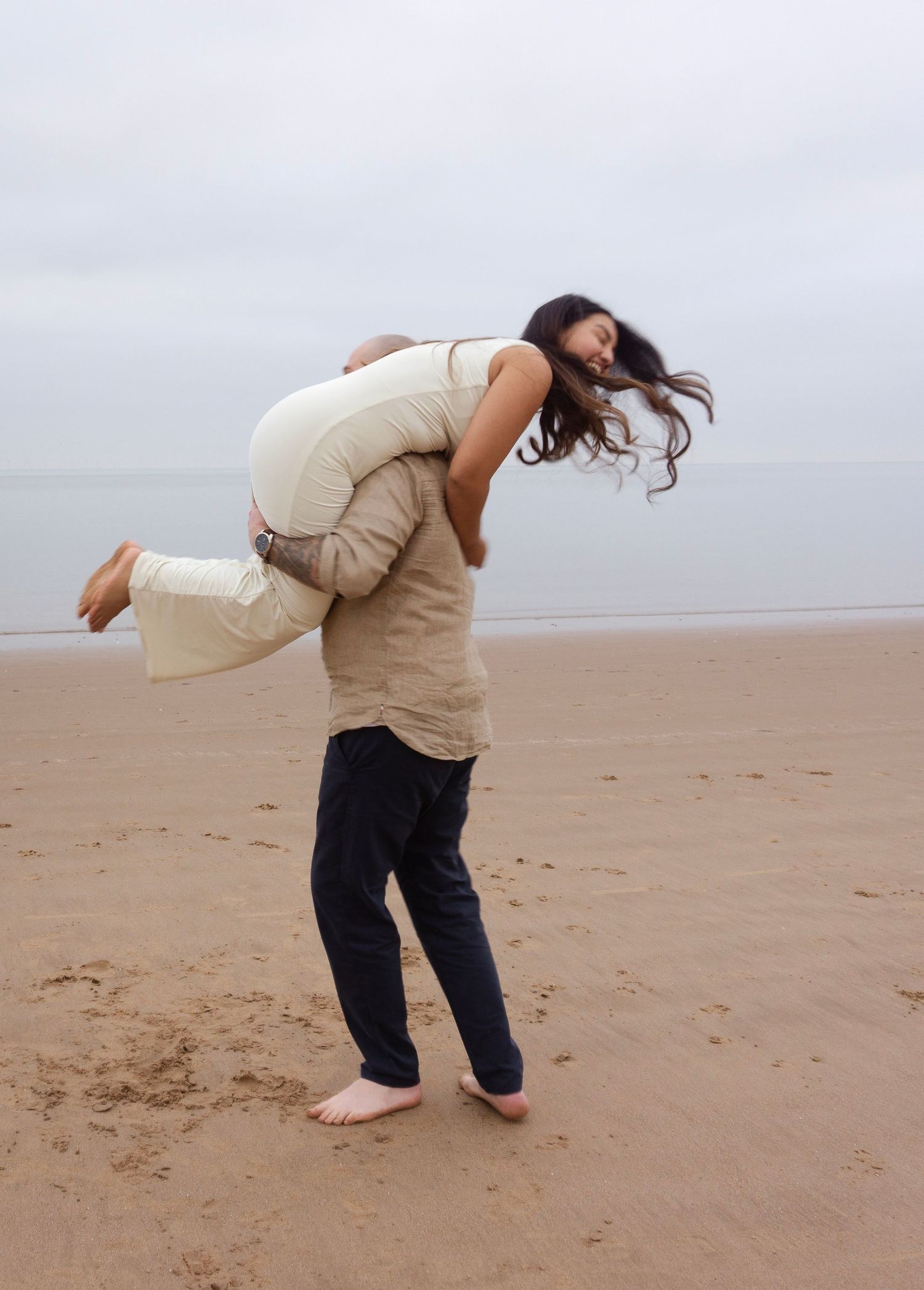 lifting photo of engaged couple during their photo session in the beach