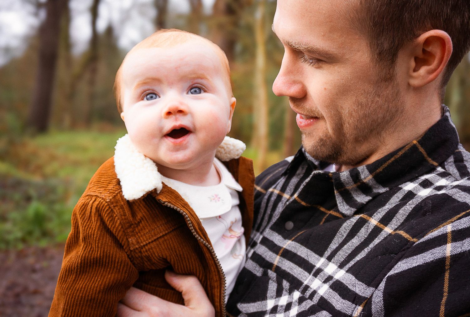 happy baby being carried by dad during their photo session in the woodlands