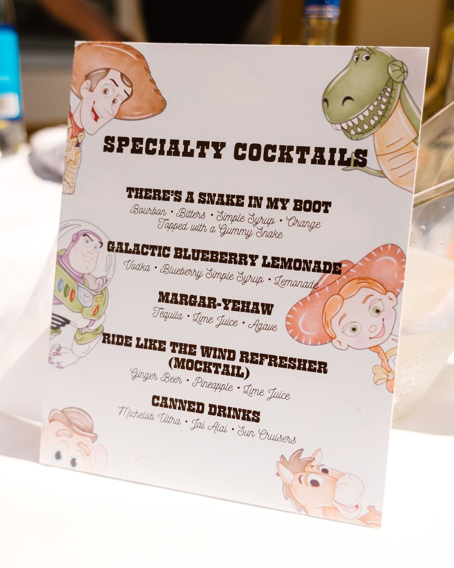 Toy Story themed specialty cocktails menu featuring Woody, Buzz, Rex, and Jessie illustrations.