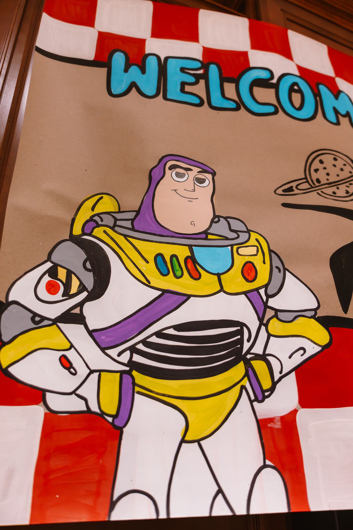 Hand-painted Buzz Lightyear welcome banner with red checkered border for Toy Story birthday party.