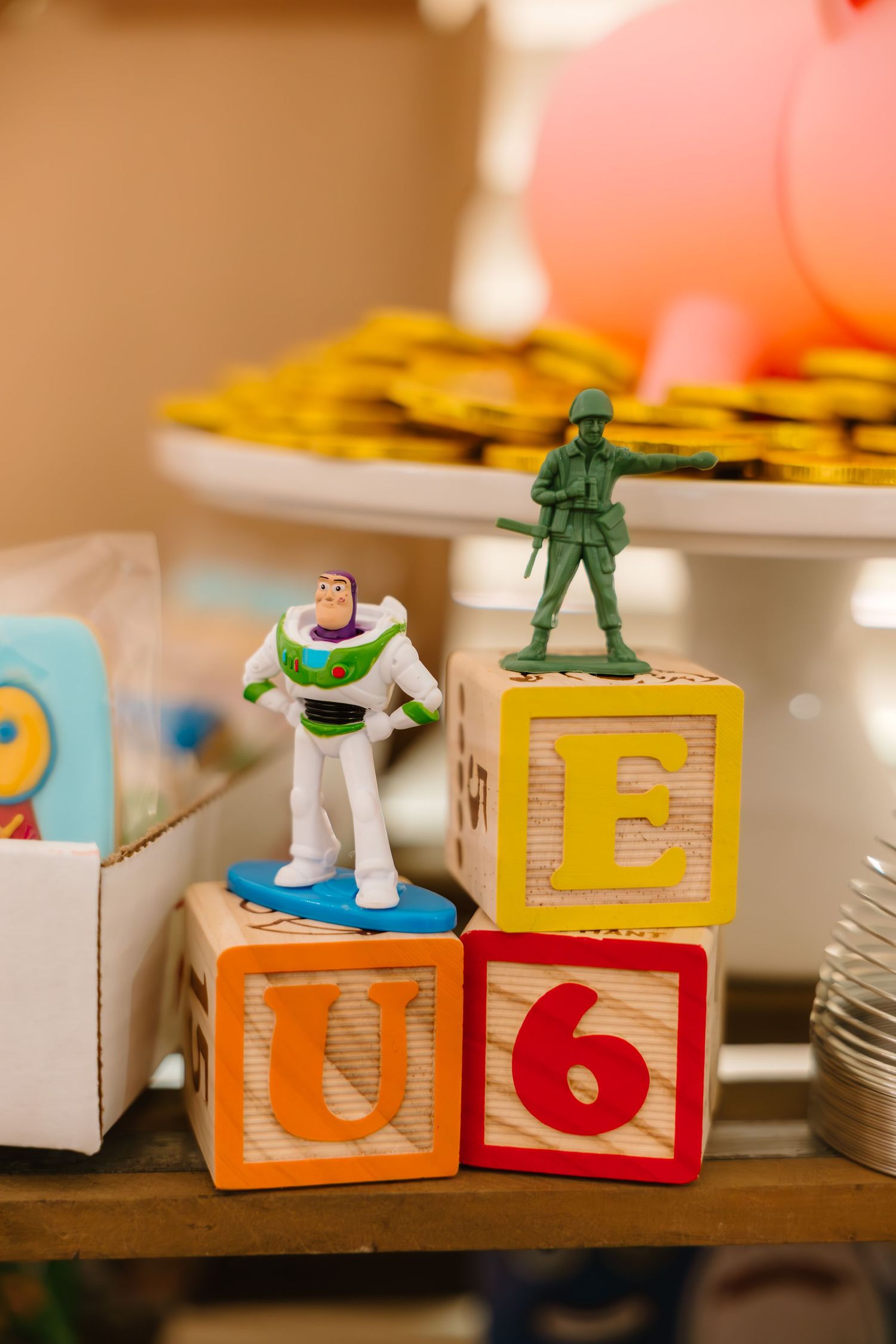 Buzz Lightyear and army soldier figurines displayed on stacked alphabet blocks at Toy Story party.