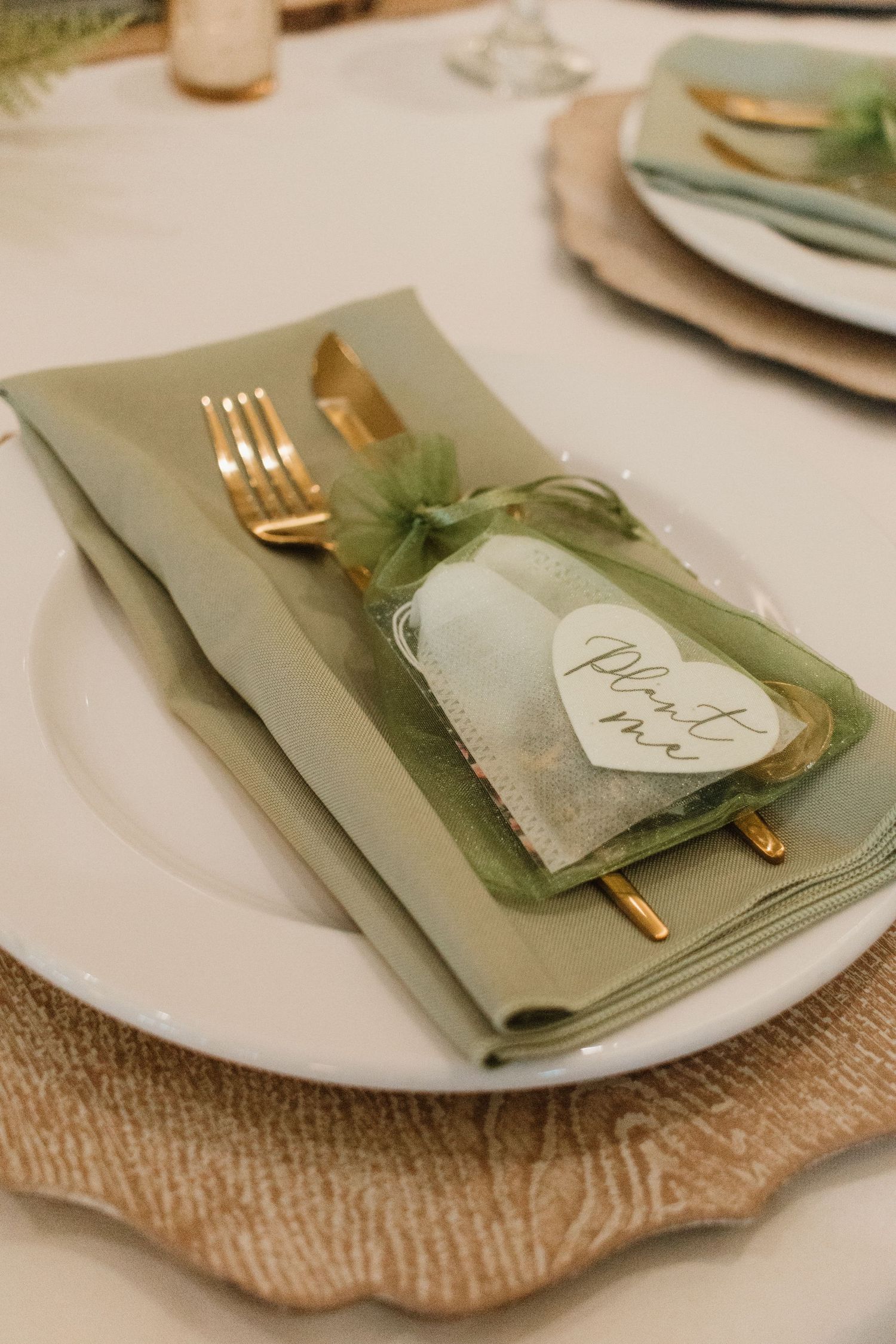 Elegant green table setting with gold cutlery and a plant me seed packet favor.