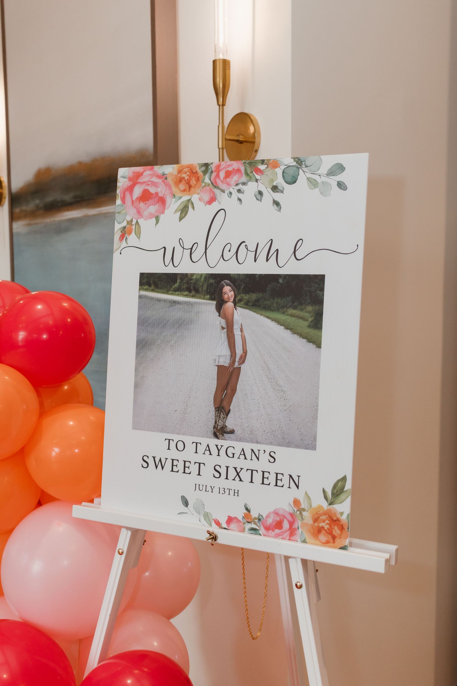 Sweet Sixteen welcome sign for Taygan on an easel with floral design and balloon arch.