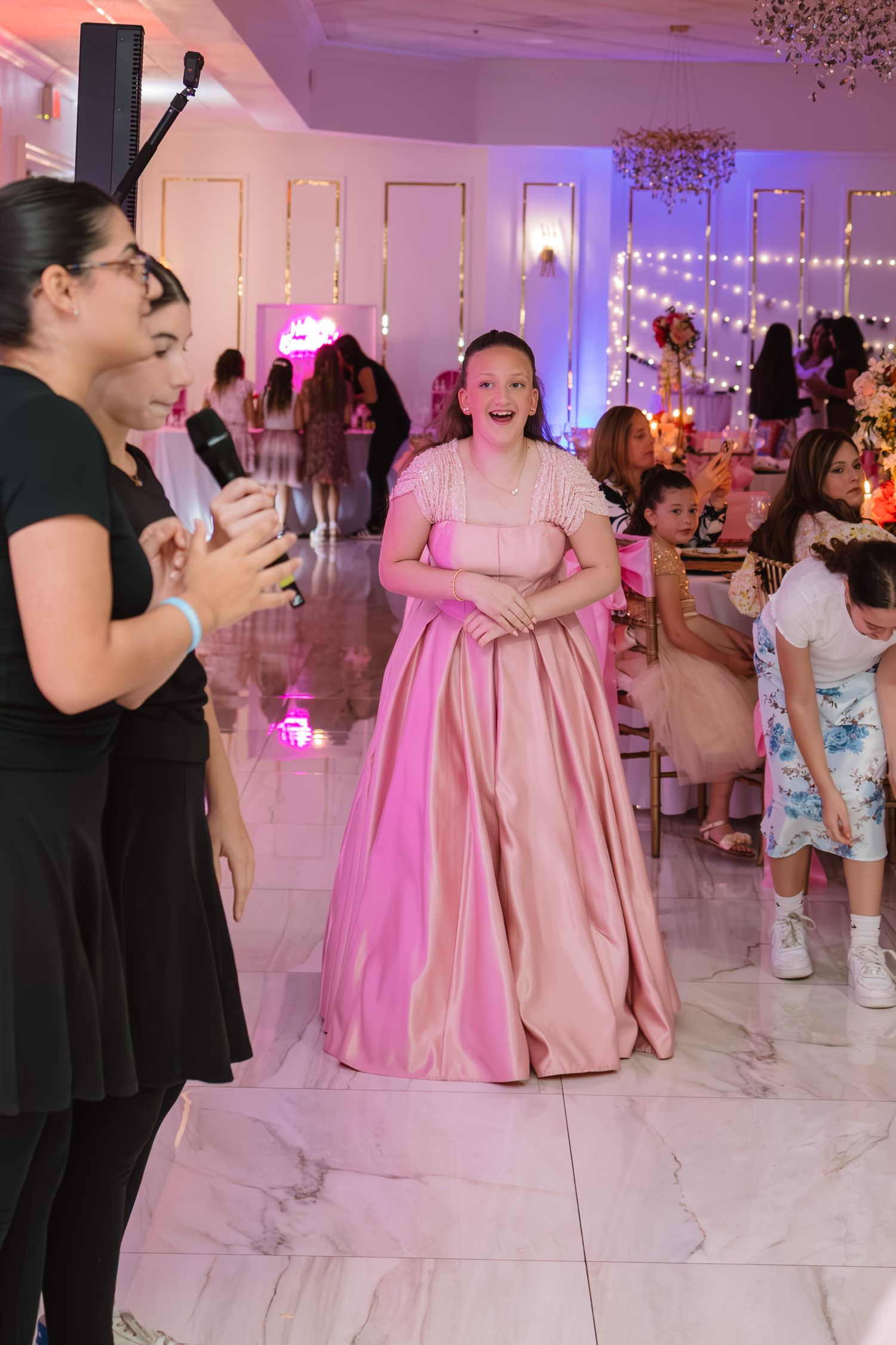 Girl in pink ball gown standing on dance floor at a glamorous birthday party.