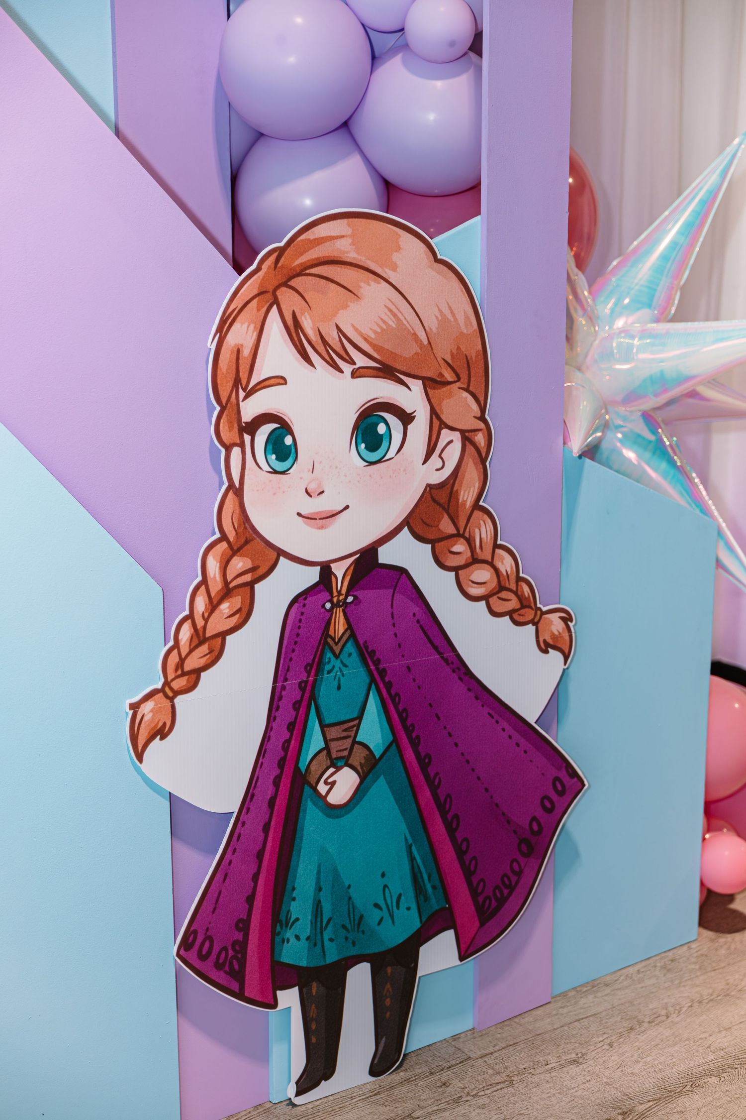 Chibi-style Anna from Frozen as a decorative cutout at a birthday party backdrop.