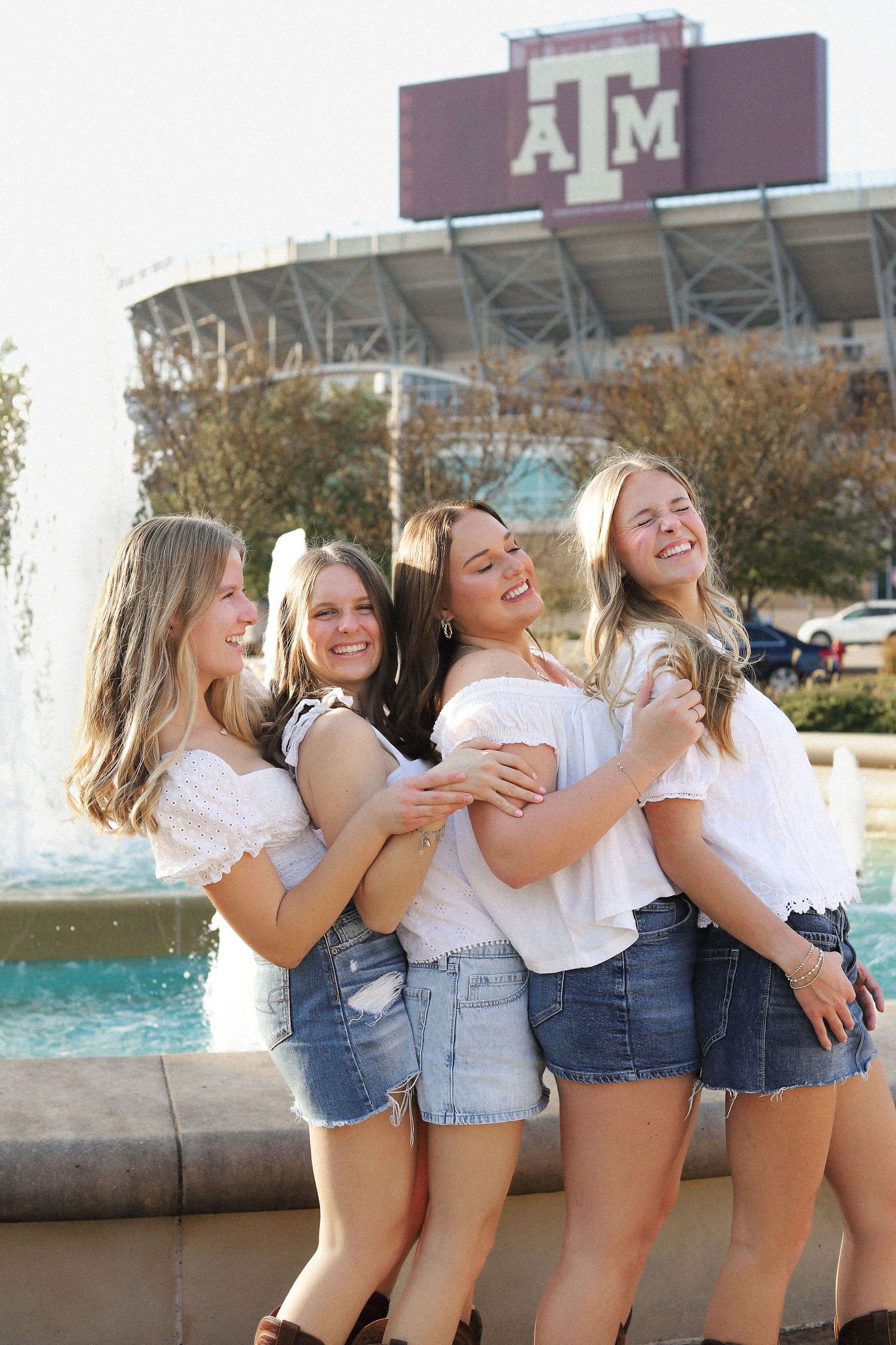 Group shares candid moments during casual photo session by campus water feature.