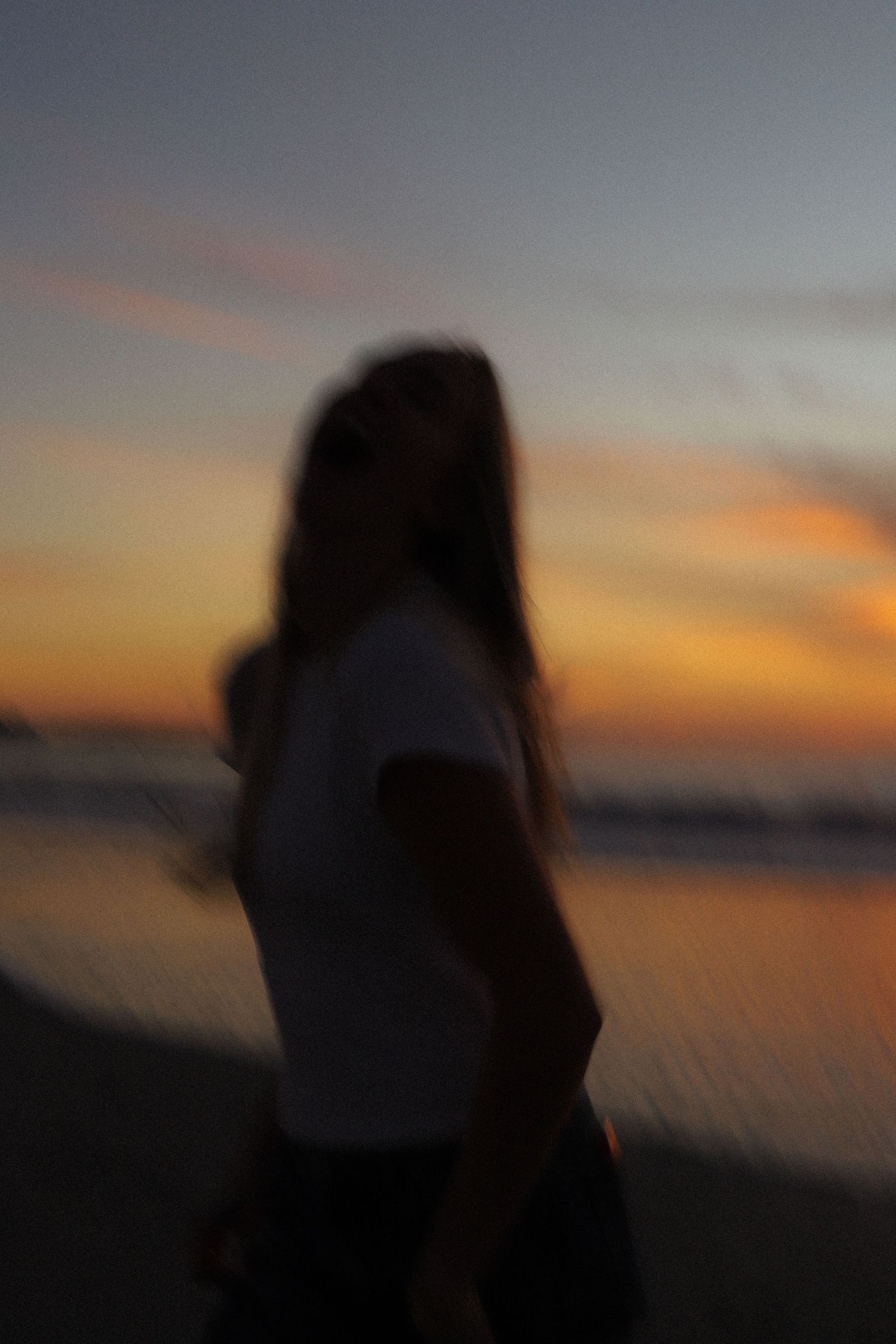 A series of silhouettes against a vibrant orange and purple sunset sky over a beach horizon.