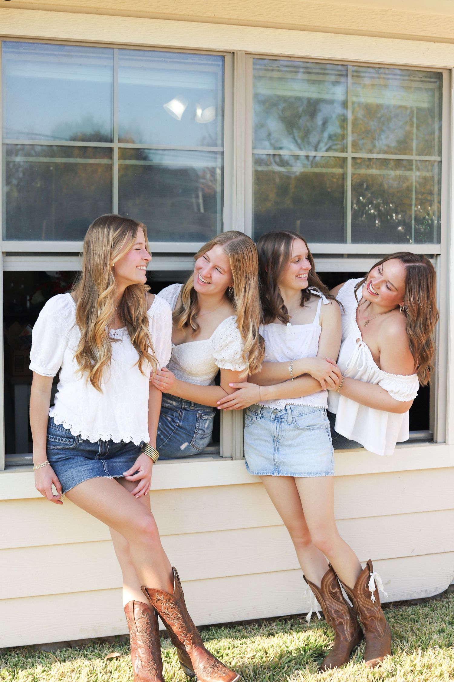 Group wearing cowboy boots and matching outfits pose along building windows.