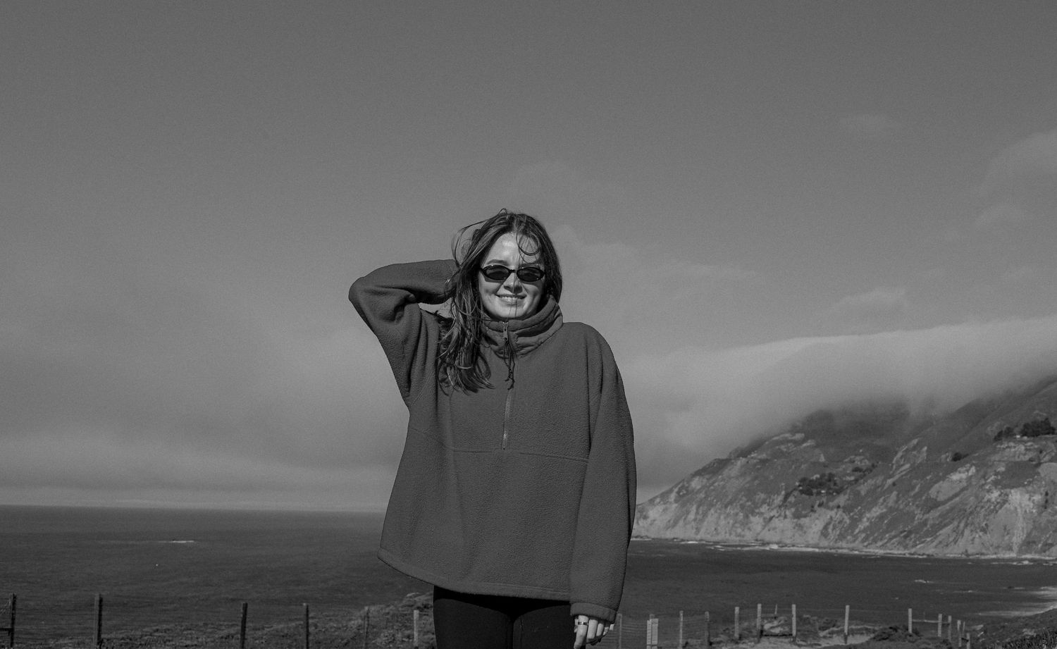A black and white landscape photo shows a silhouetted figure standing against a dramatic mountain backdrop.