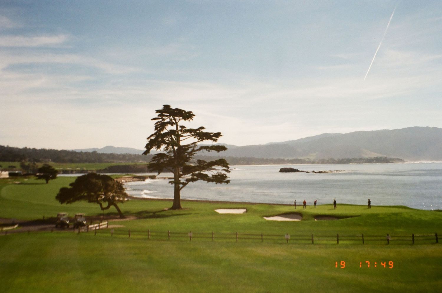 Scenic coastal golf course with dramatic cliffs, cypress trees, and ocean views along Pebble Beach, California.