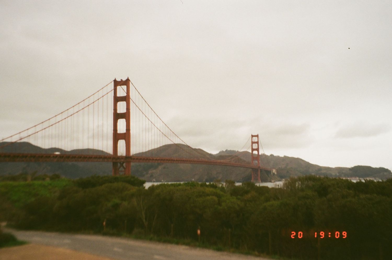 Vintage-style photograph of the Golden Gate Bridge spanning across San Francisco Bay under overcast skies.
