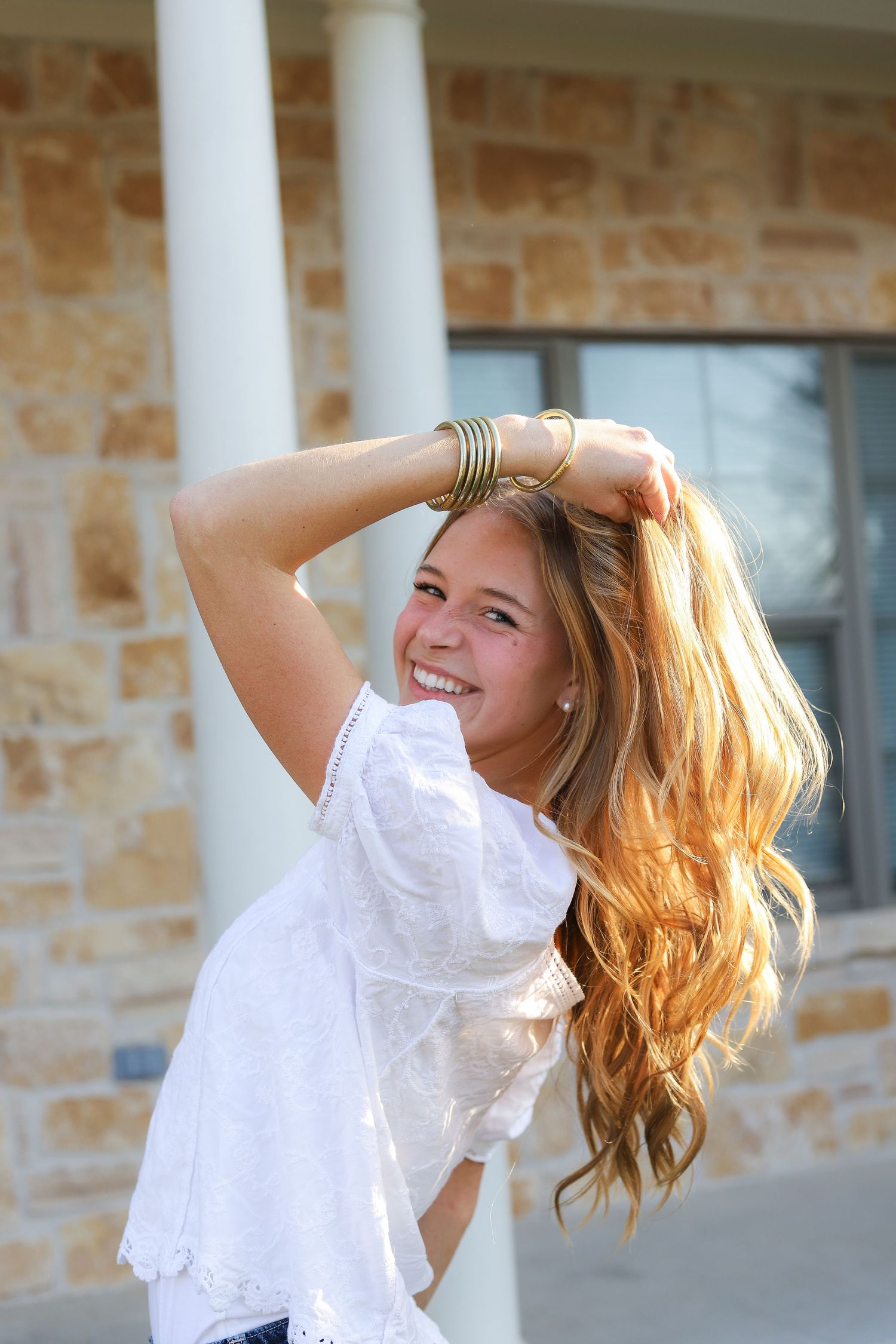 Sunlit portrait series showing movement and hair tossing against white columns and stone wall backdrop.