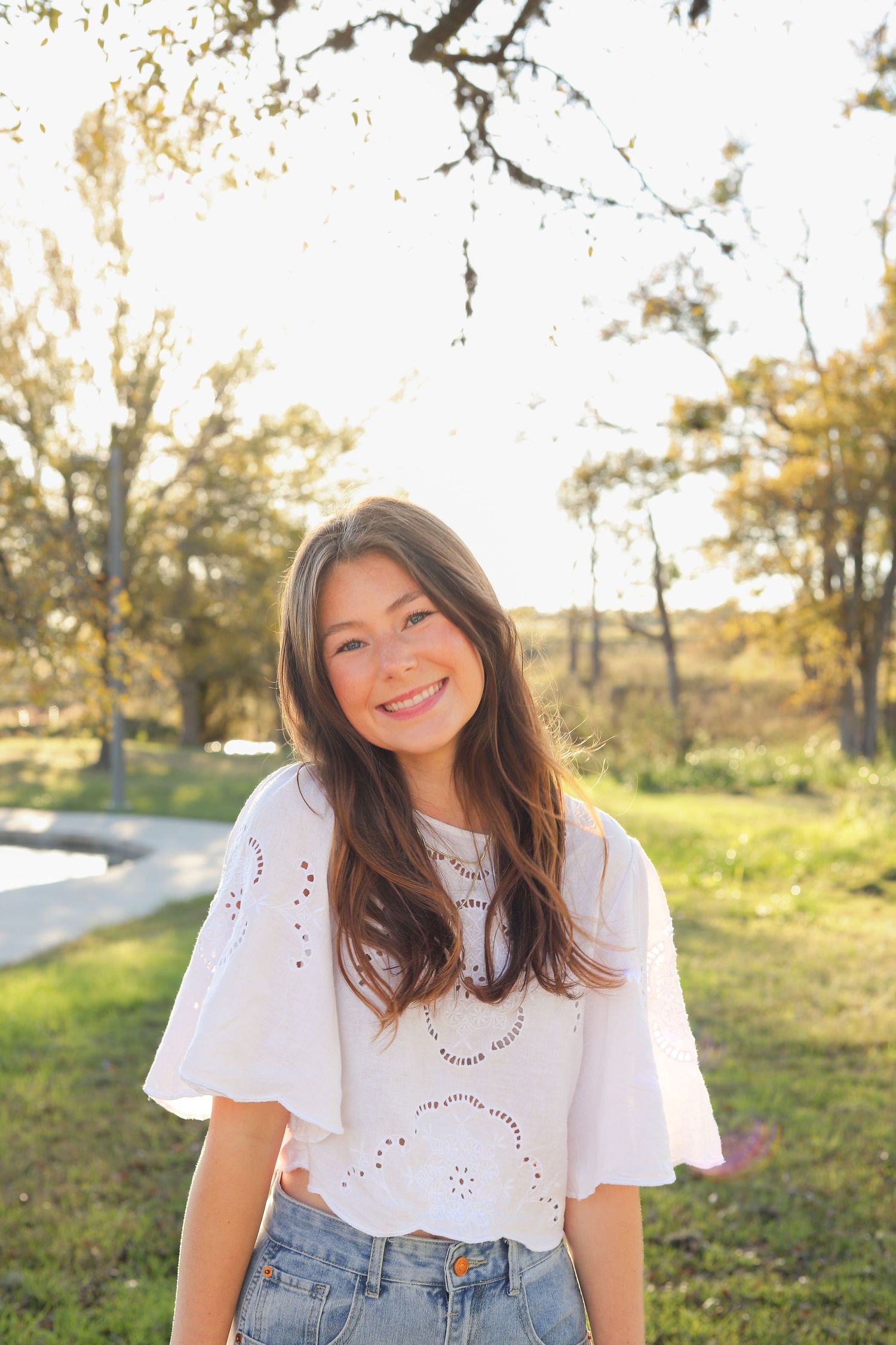 Candid outdoor shot showing a bright smile and classic white and denim outfit combination.