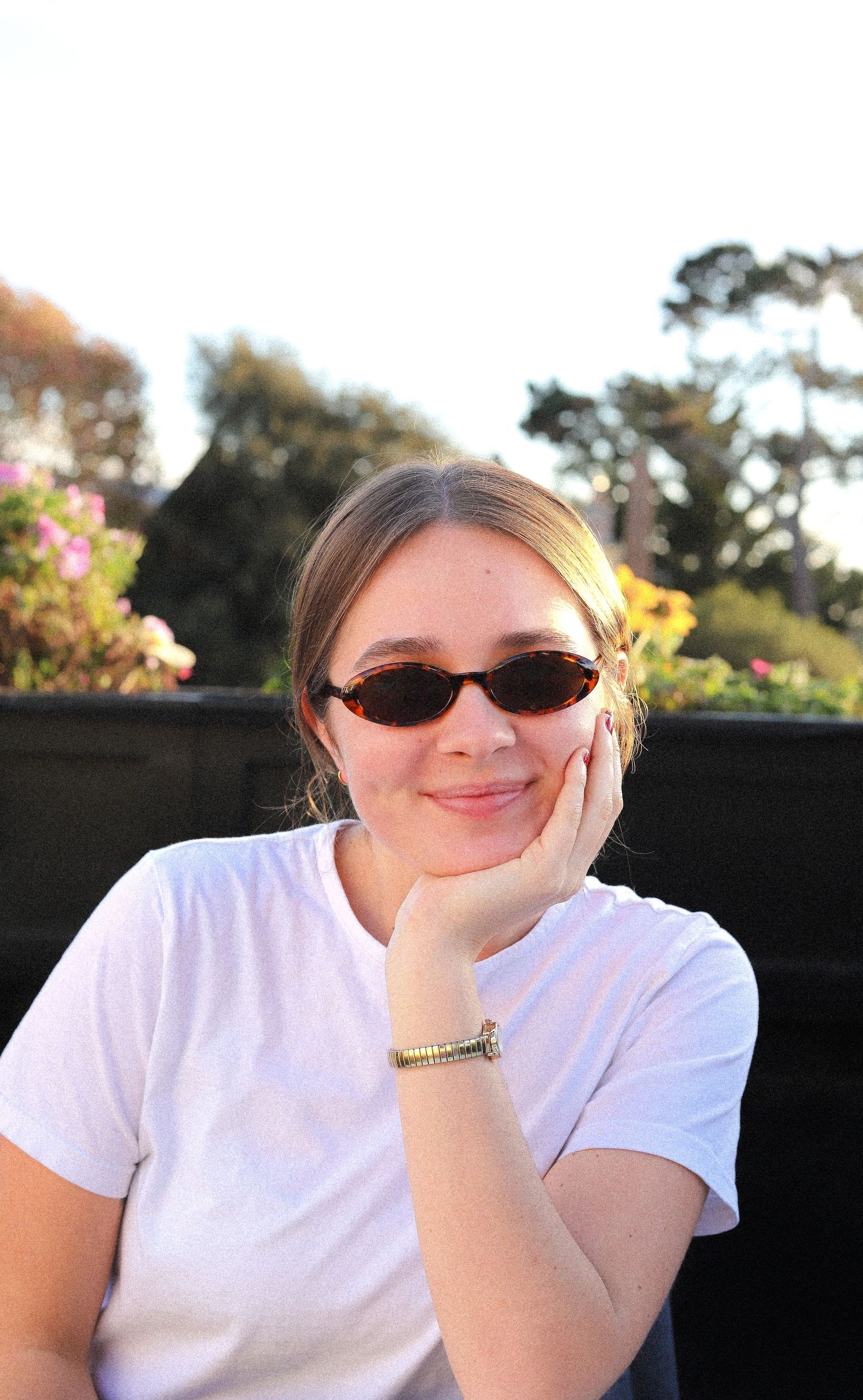 Three photos of someone in a white t-shirt sitting outdoors with sunglasses and resting their head on their hand.