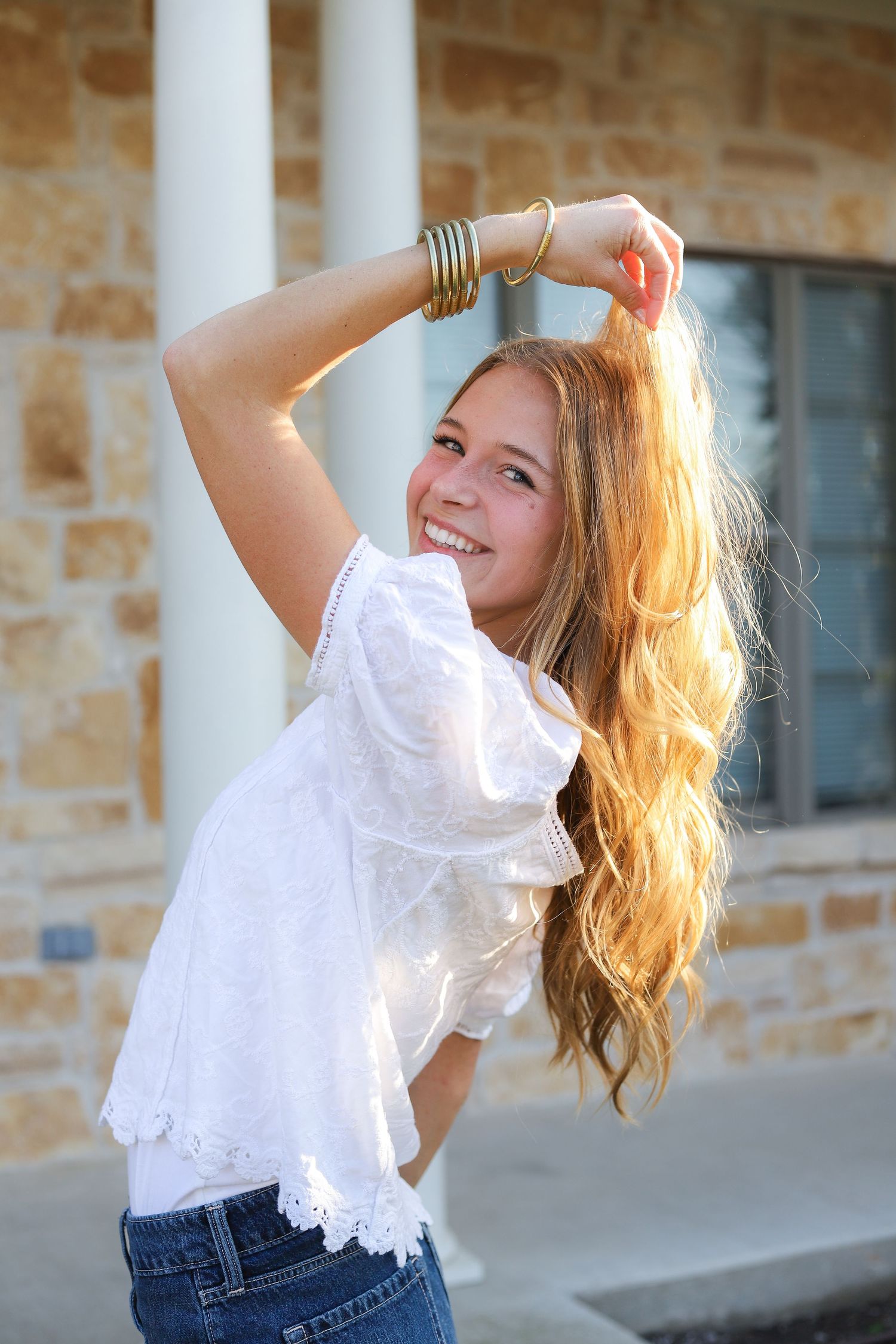 Candid fashion portraits with white lace top and natural lighting against stone building exterior.