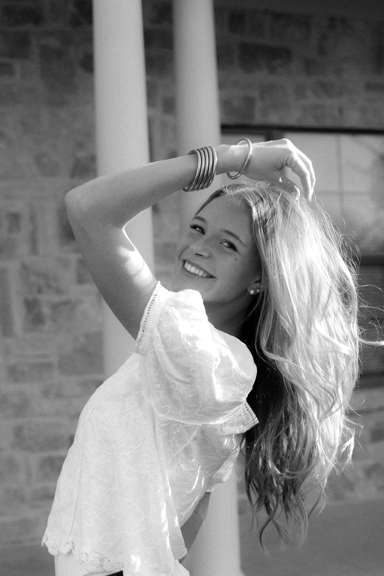 Black and white portrait series with flowing white fabric against brick wall.