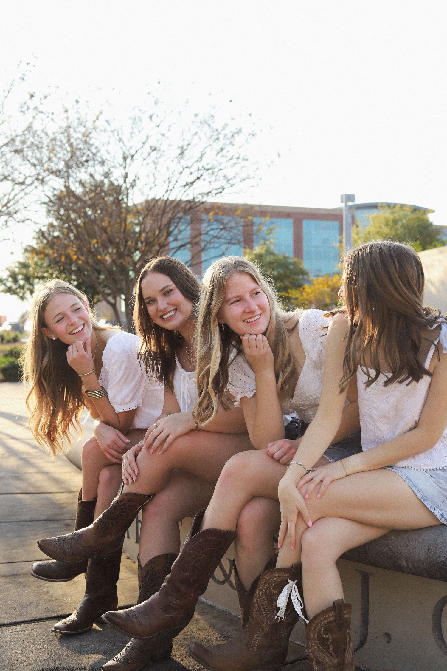 Group in casual attire and boots sit together on ledge during golden hour.