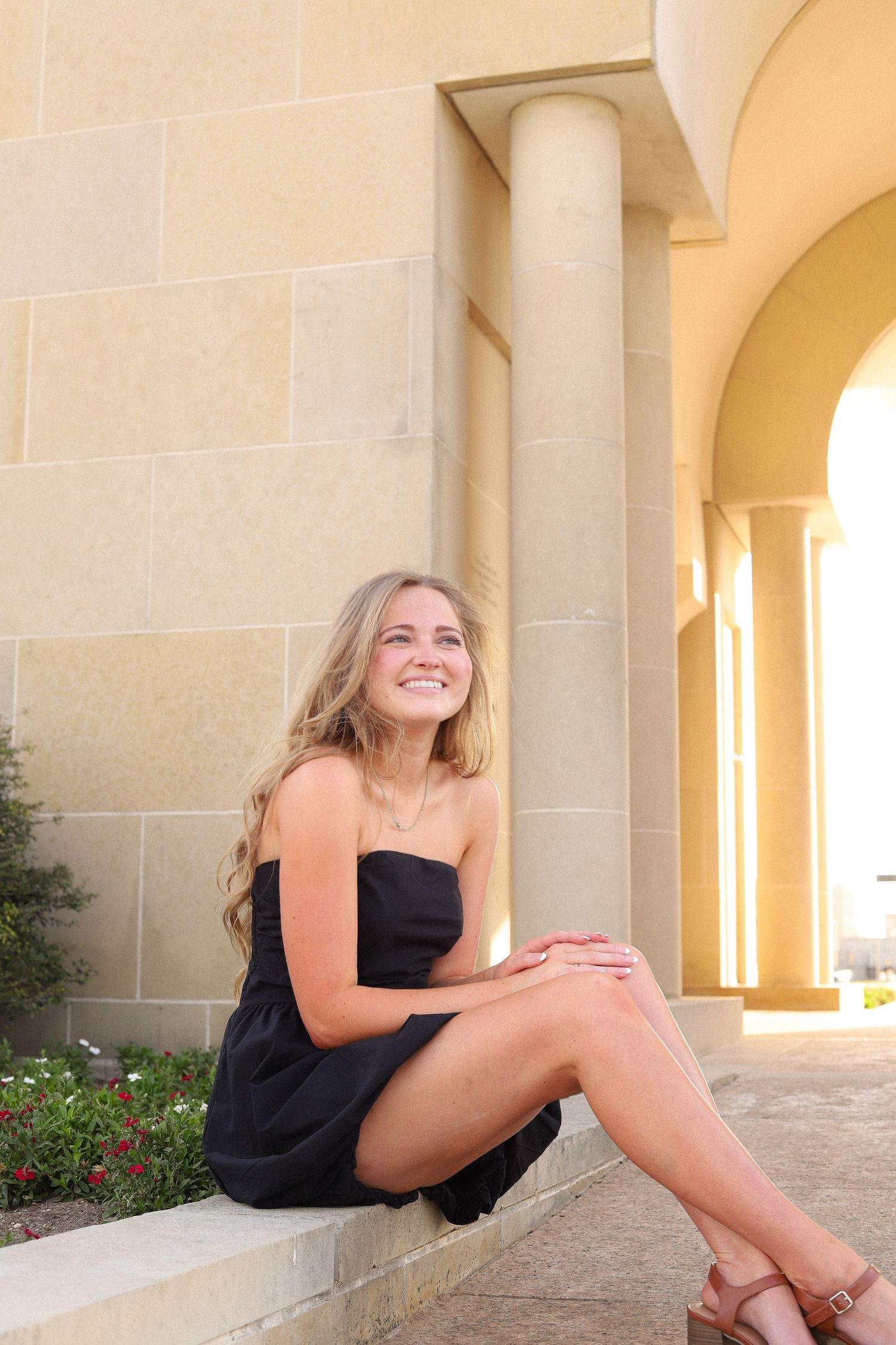 Multiple shots of someone in black dress posing casually by stone columns and arches.