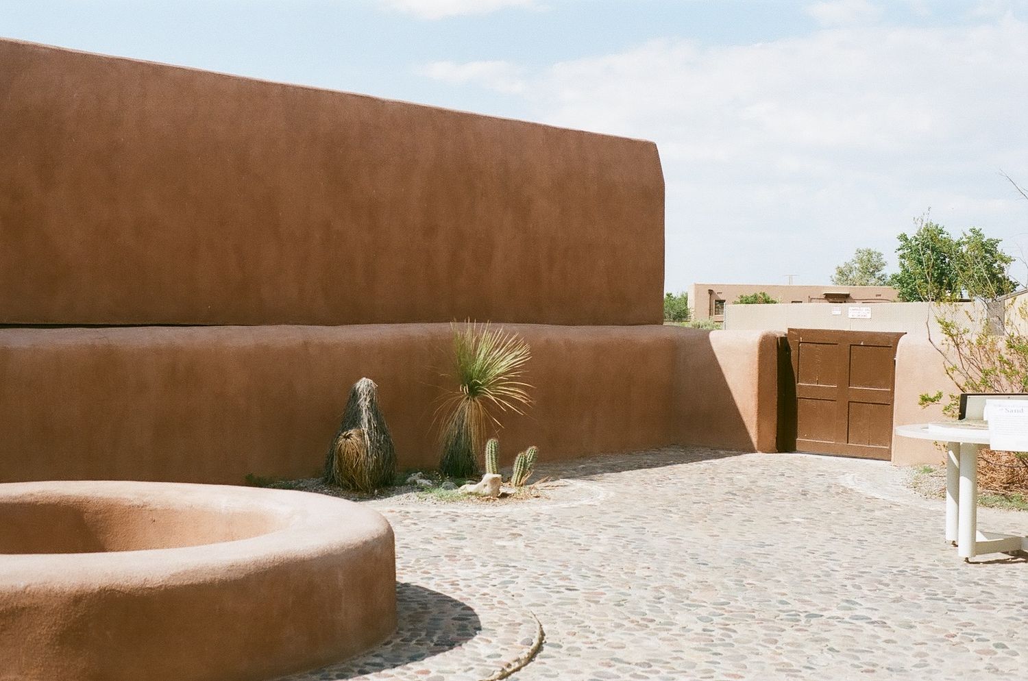 Adobe-style architecture with curved walls and desert landscaping under blue sky.