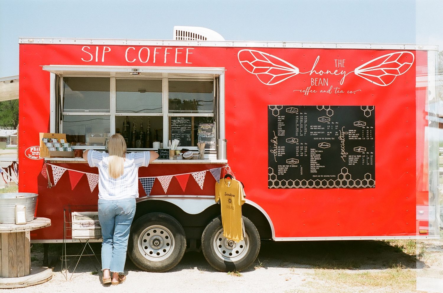 Bright red food truck with 'Sip Coffee' branding and festive bunting decorations.