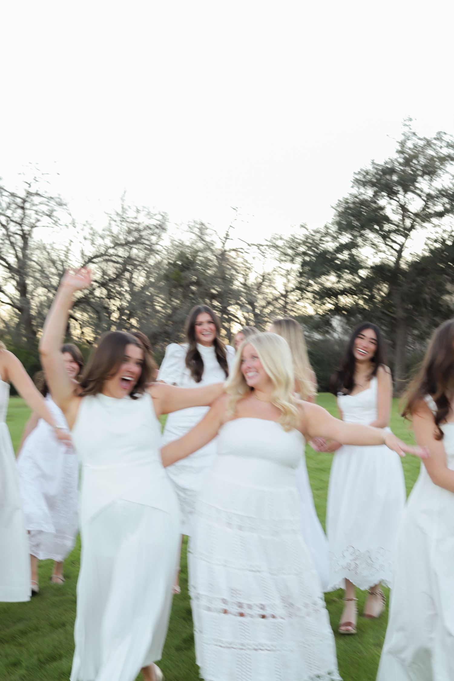 A joyful celebration captured in motion as people in white dresses dance in a circle on grass.