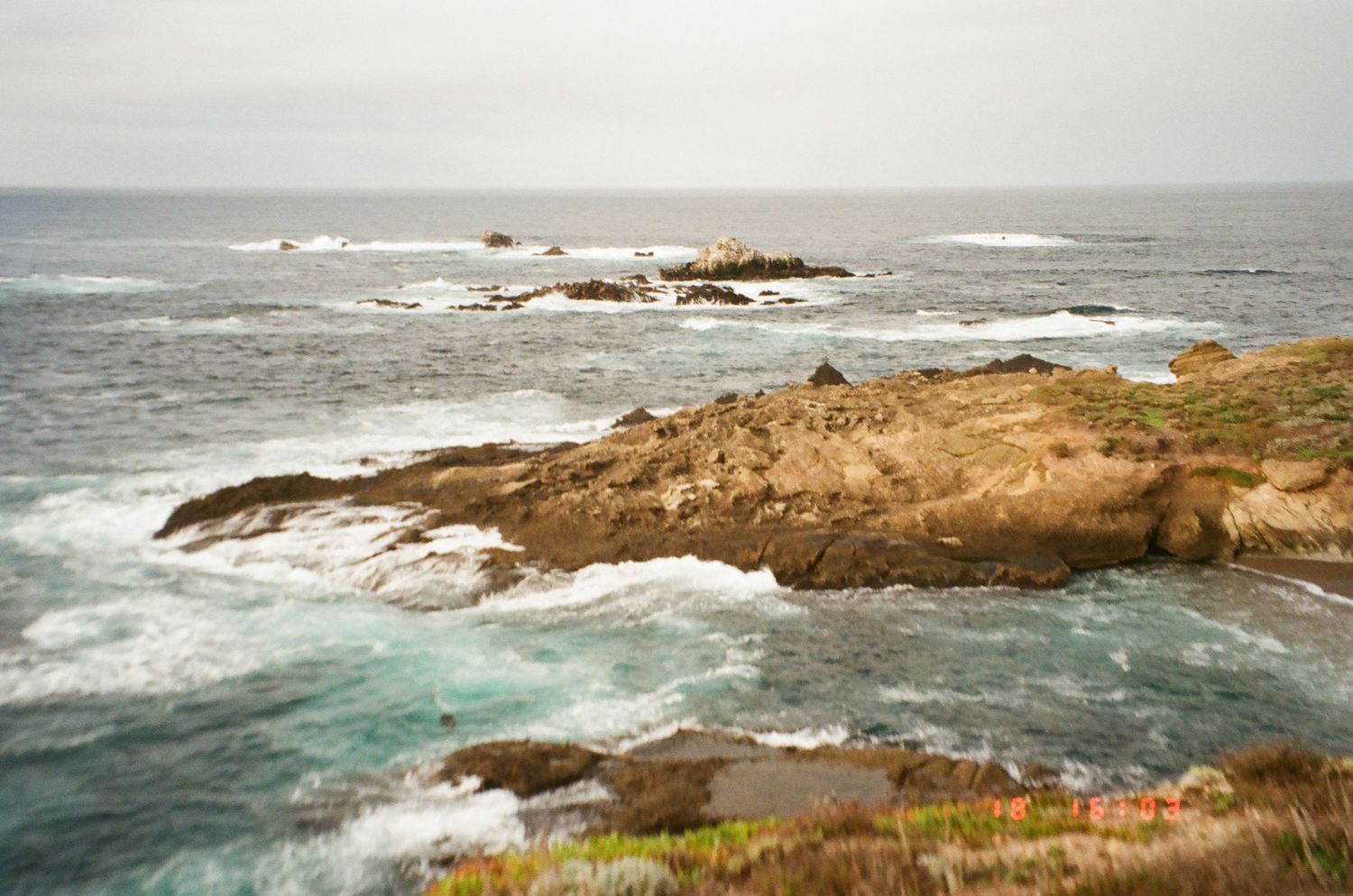Rocky coastal landscape with crashing waves and rugged cliffs along a scenic ocean shoreline.
