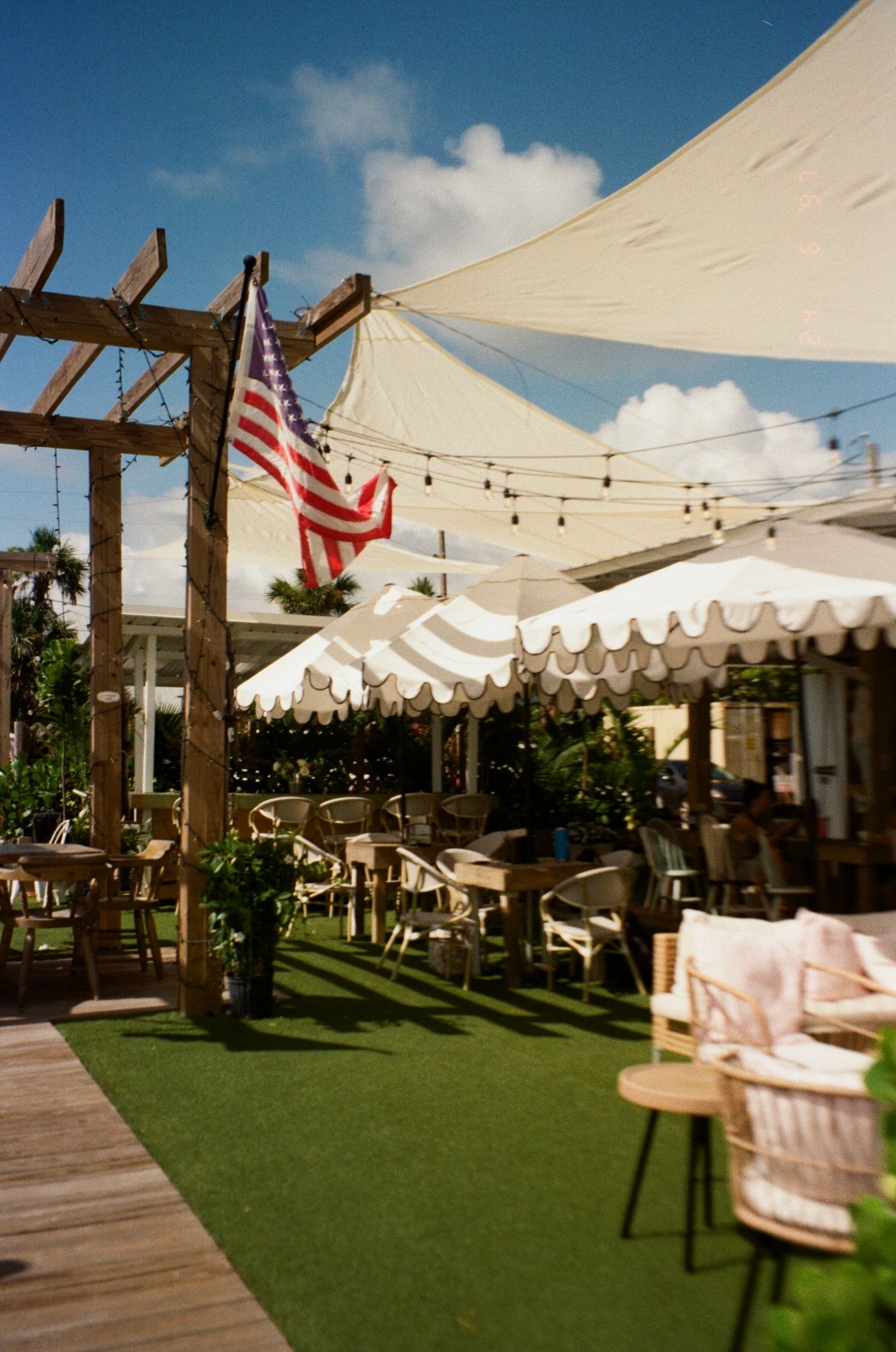 White tent canopies and wooden posts create an elegant outdoor event space with string lights and American flags.